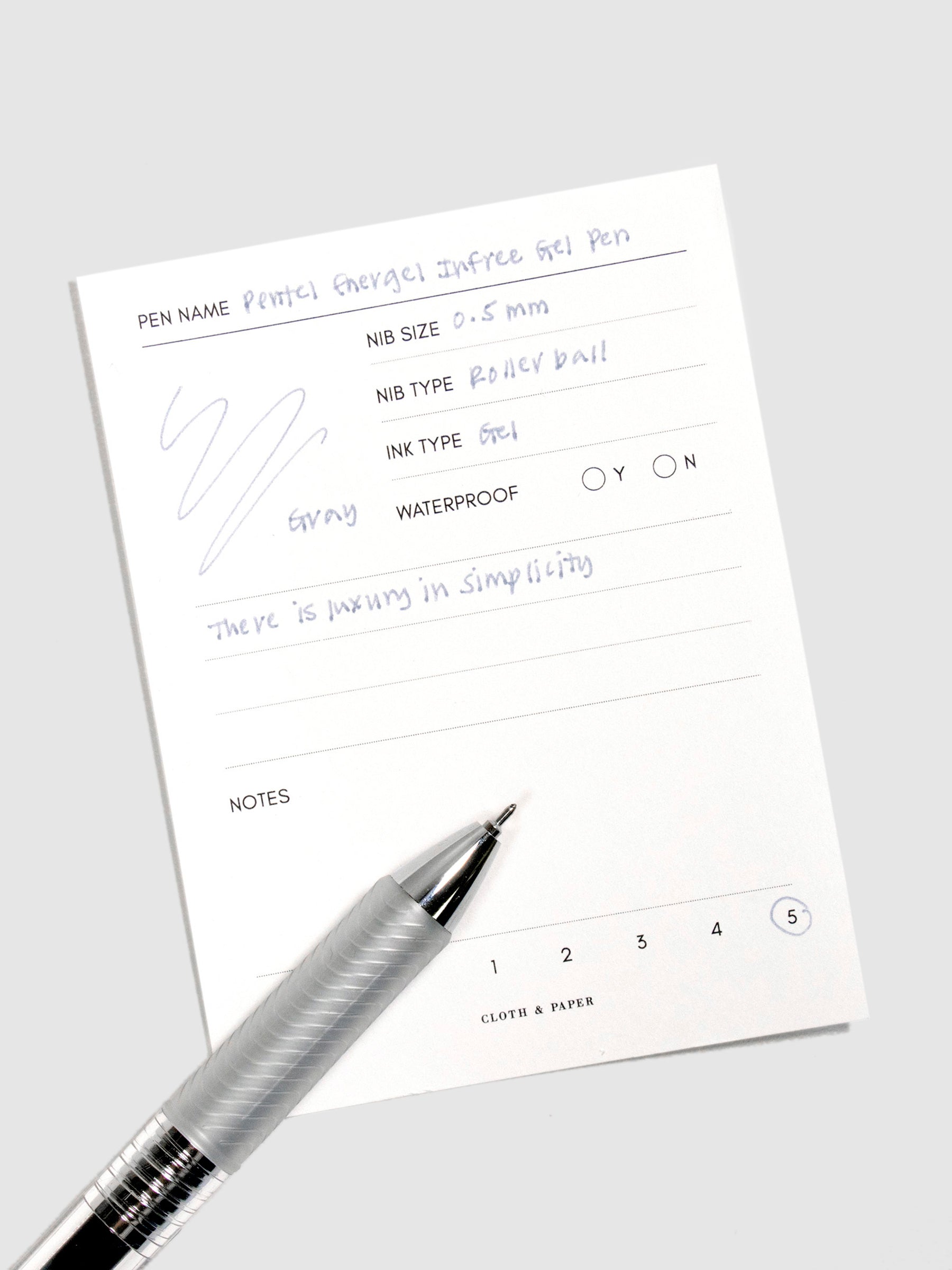 Pentel Energel Infree Gel Pen, Gray, Cloth and Paper. Close up on pen nib resting on pen test sheet.