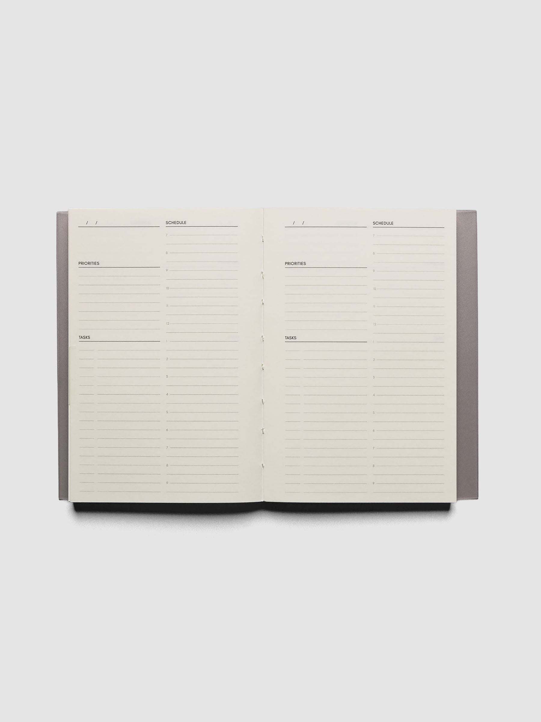 Perfect Bound Notebook | CP Petite | Undated Daily | Verona shown open, laying flat, on a neutral background. Each page has a header for date, priorities, tasks, and schedule.