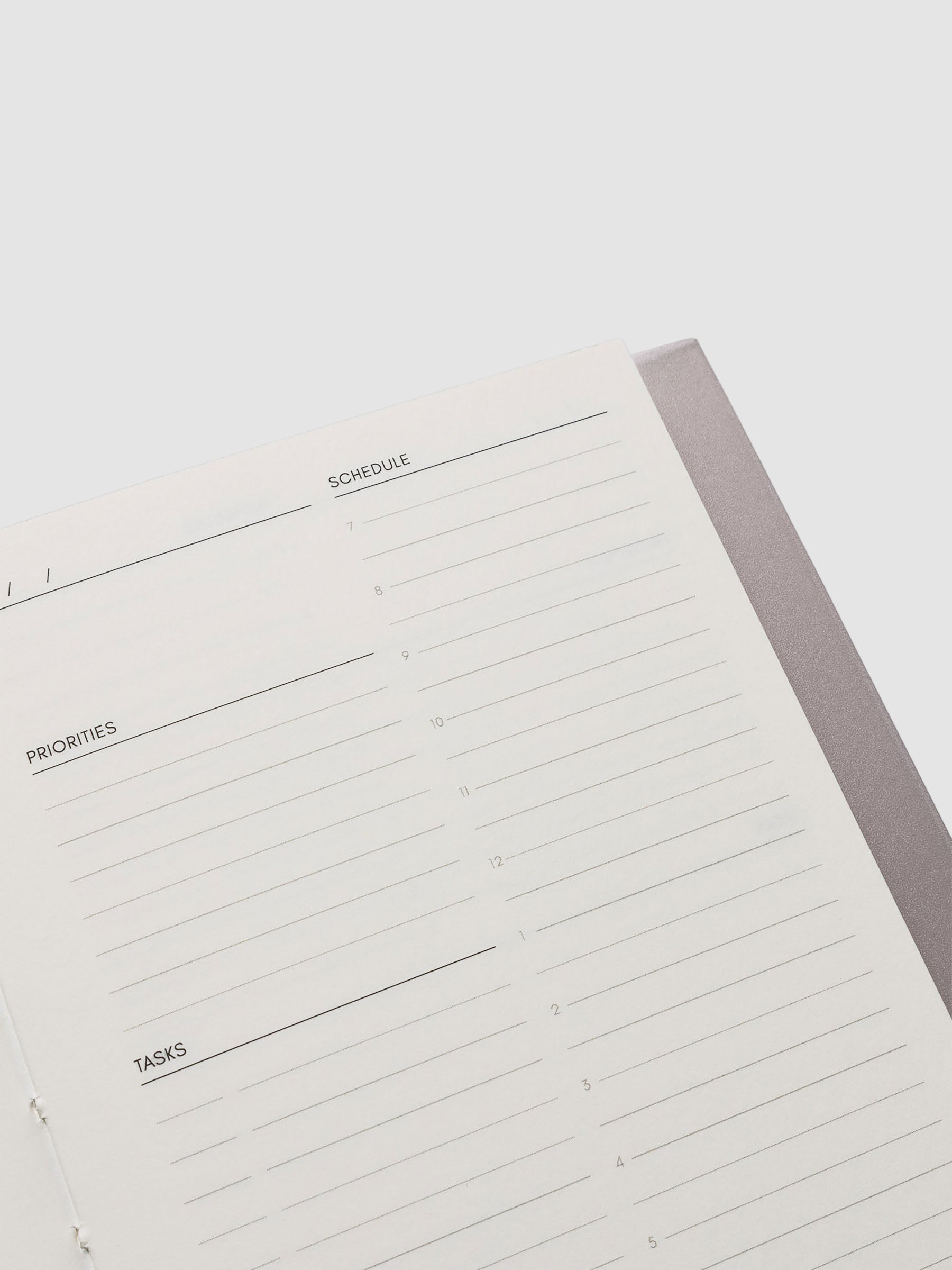 Perfect Bound Notebook | CP Petite | Undated Daily | Verona shown open, laying flat, on a neutral background. Each page has a header for date, priorities, tasks, and schedule.
