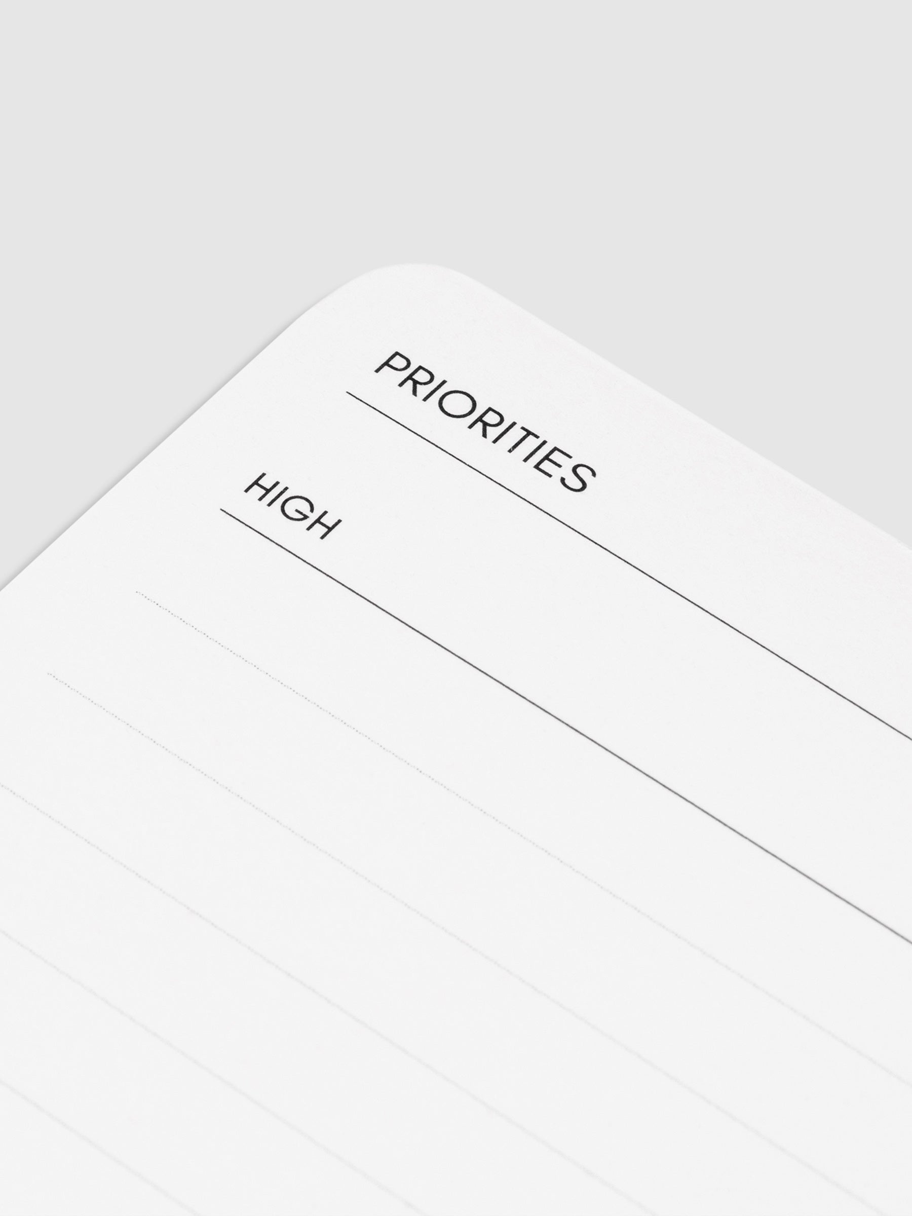 Closeup of text on notepad reading "priorities" and the high priority task list.