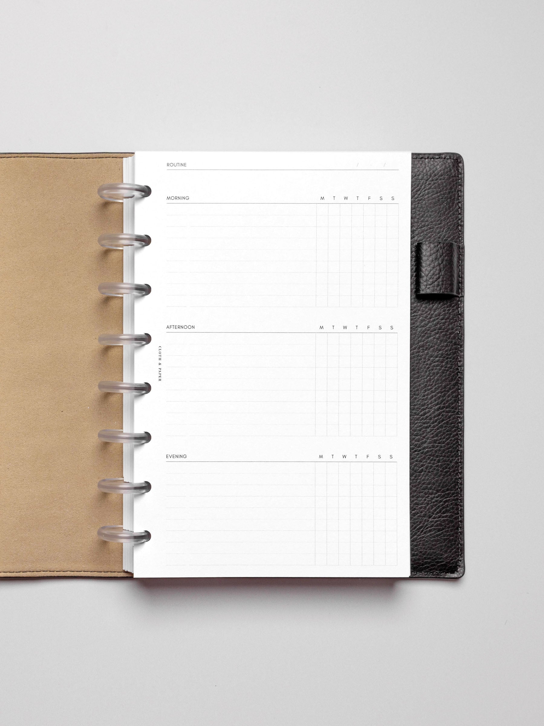 Insert in use inside a black discbound planner agenda system. Spread displays two days' worth of morning, afternoon, and evening routines.