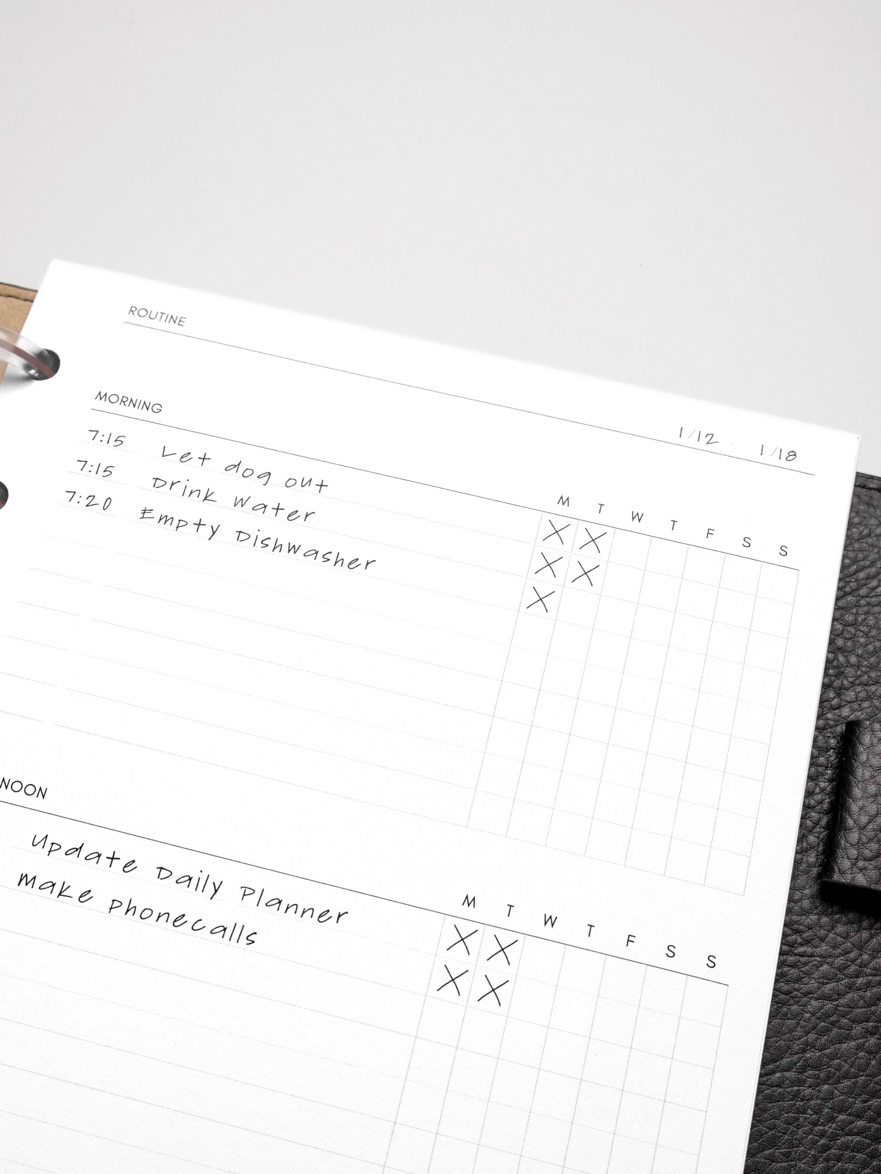 Closeup of insert in use inside a black discbound planner system. Focus is on the morning and afternoon sections of the routine section.