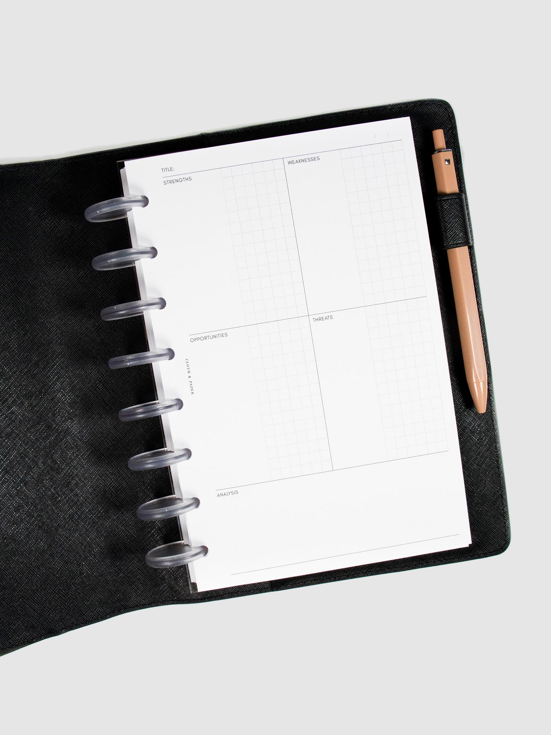 SWOT Analysis Planner Inserts in the Refreshed Layout styled inside a discbound planner. The planner is in a black leather planner cover with a pen tucked into the pen loop.