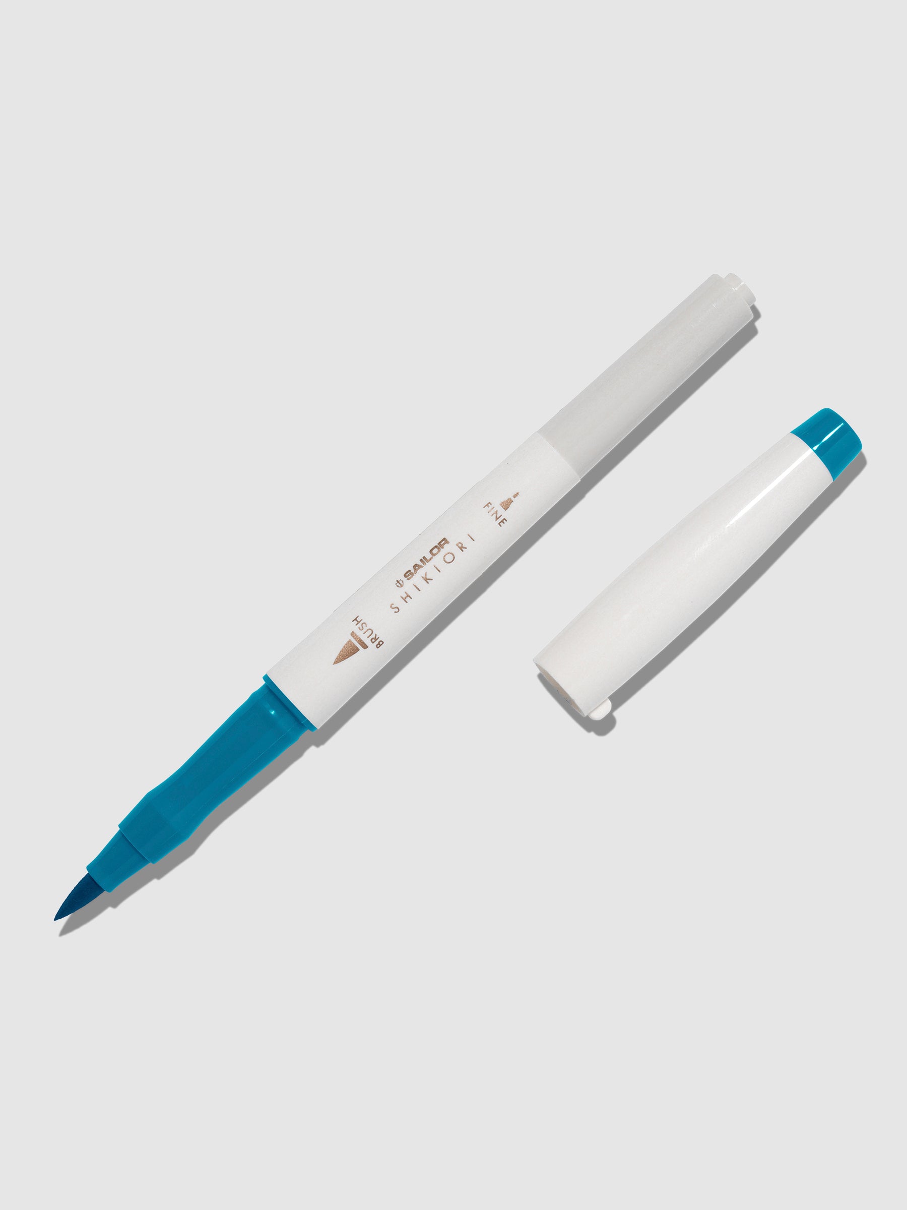 Brush pen displayed on a neutral background. It is uncapped with its brush nib exposed, and the cap lying parallel to the marker. Color pictured is Yamadori.