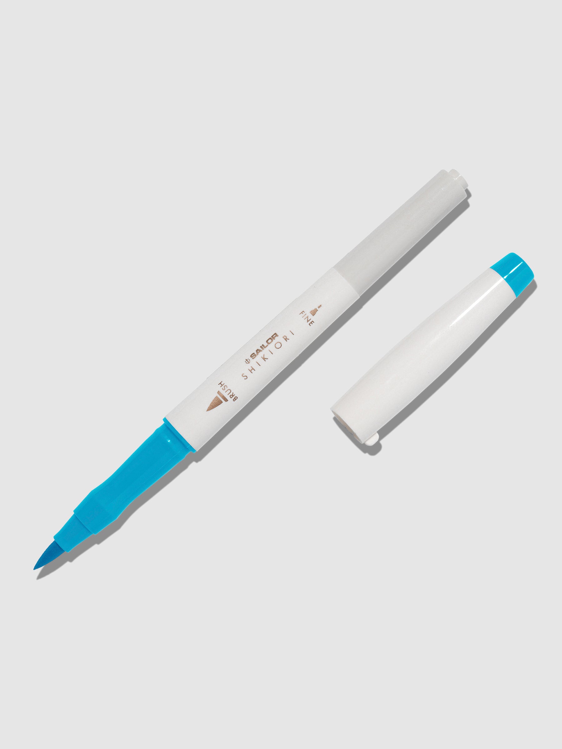 Brush pen displayed on a neutral background. It is uncapped with its brush nib exposed, and the cap lying parallel to the marker. Color pictured is Yukiakari.