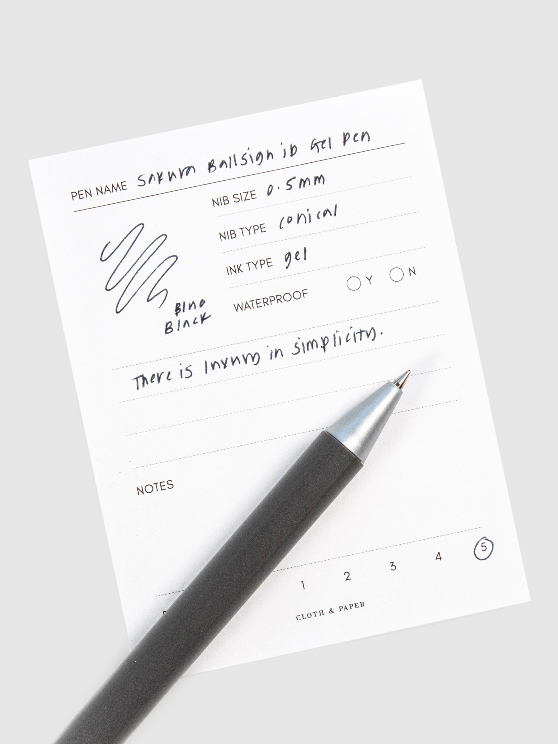 Pen in Blue Black resting on a pen test sheet displaying a writing sample detailing the pen's specs.