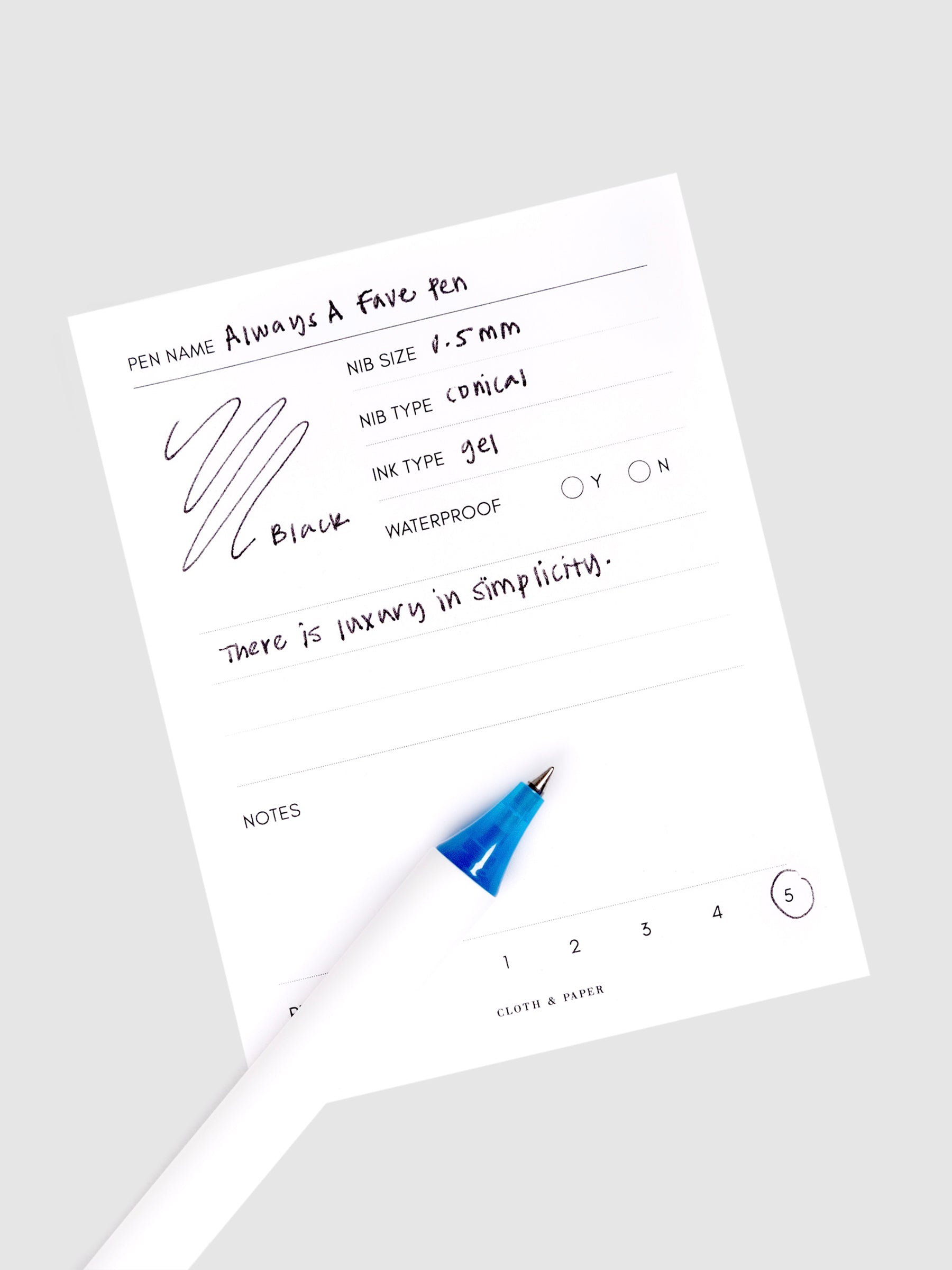 Always a Fave Pen, Dark Blue, Cloth and Paper. Pen resting on pen test sheet displaying writing sample.