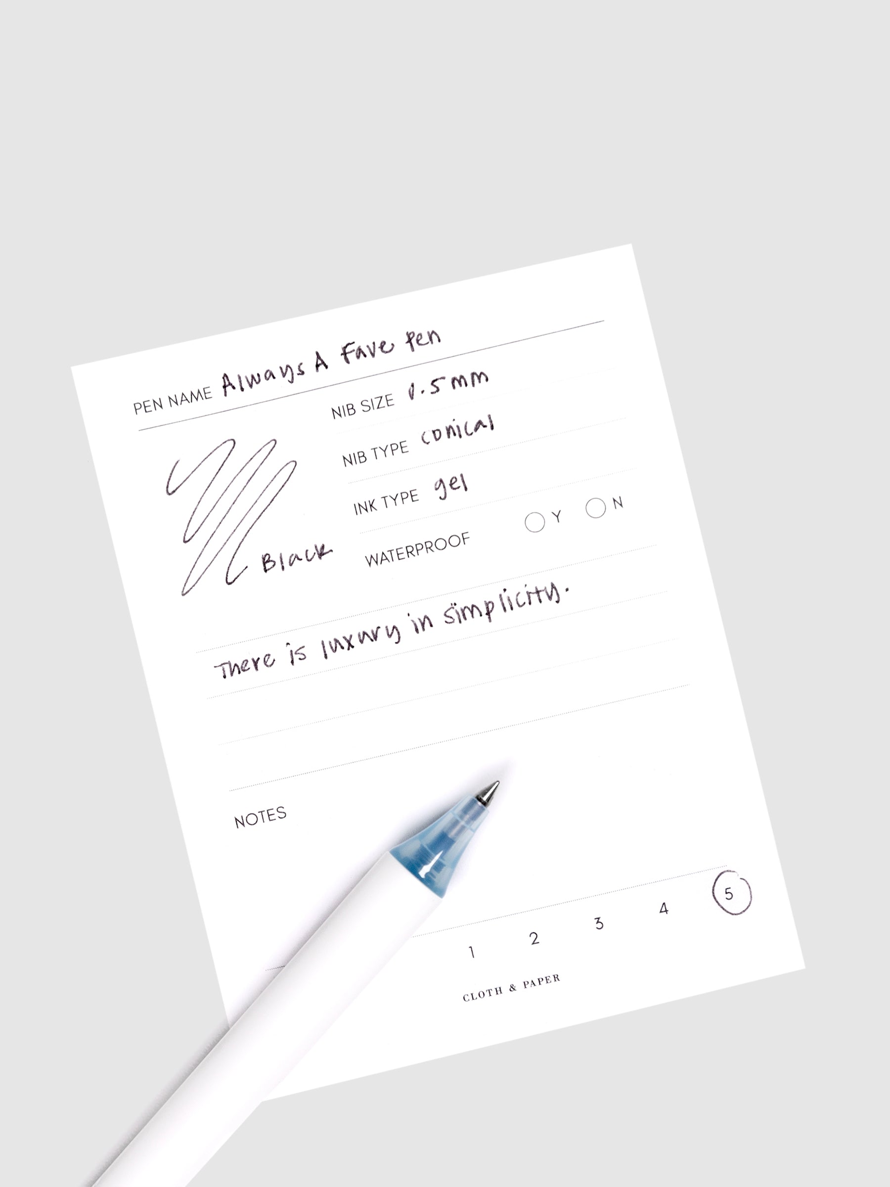 Always a Fave Pen, Light Blue, Cloth and Paper. Pen resting on pen test sheet displaying writing sample.