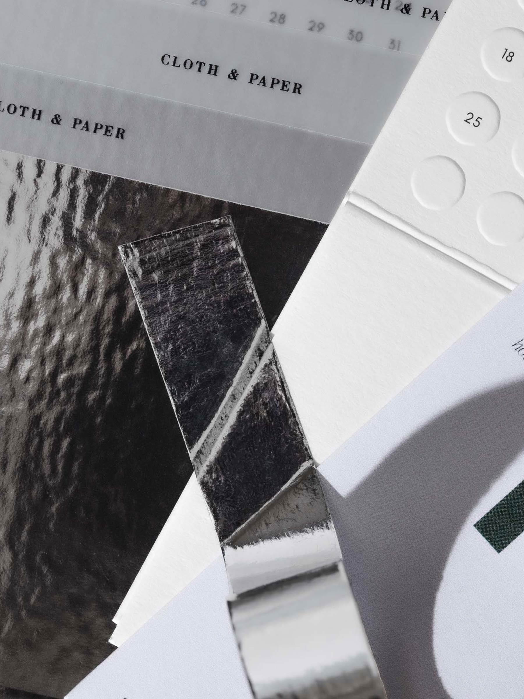 Silver tape in use - a dashboard, calendar card, and silver archive box are taped together starting from the roll.