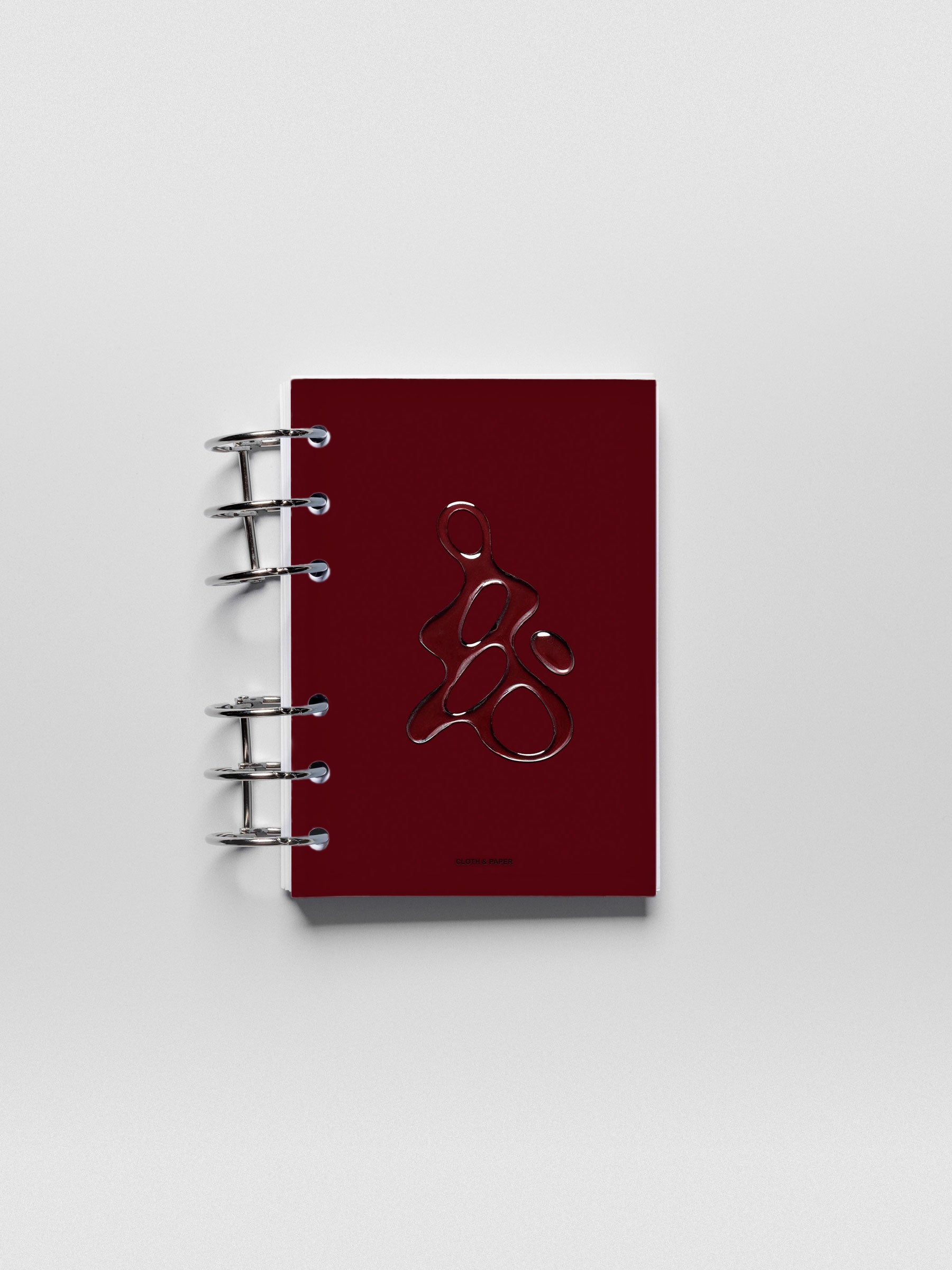 Dark red, semi-transparent, and glossy plastic planner dashboard with organic raised shape design in size A6 shown ringbound.