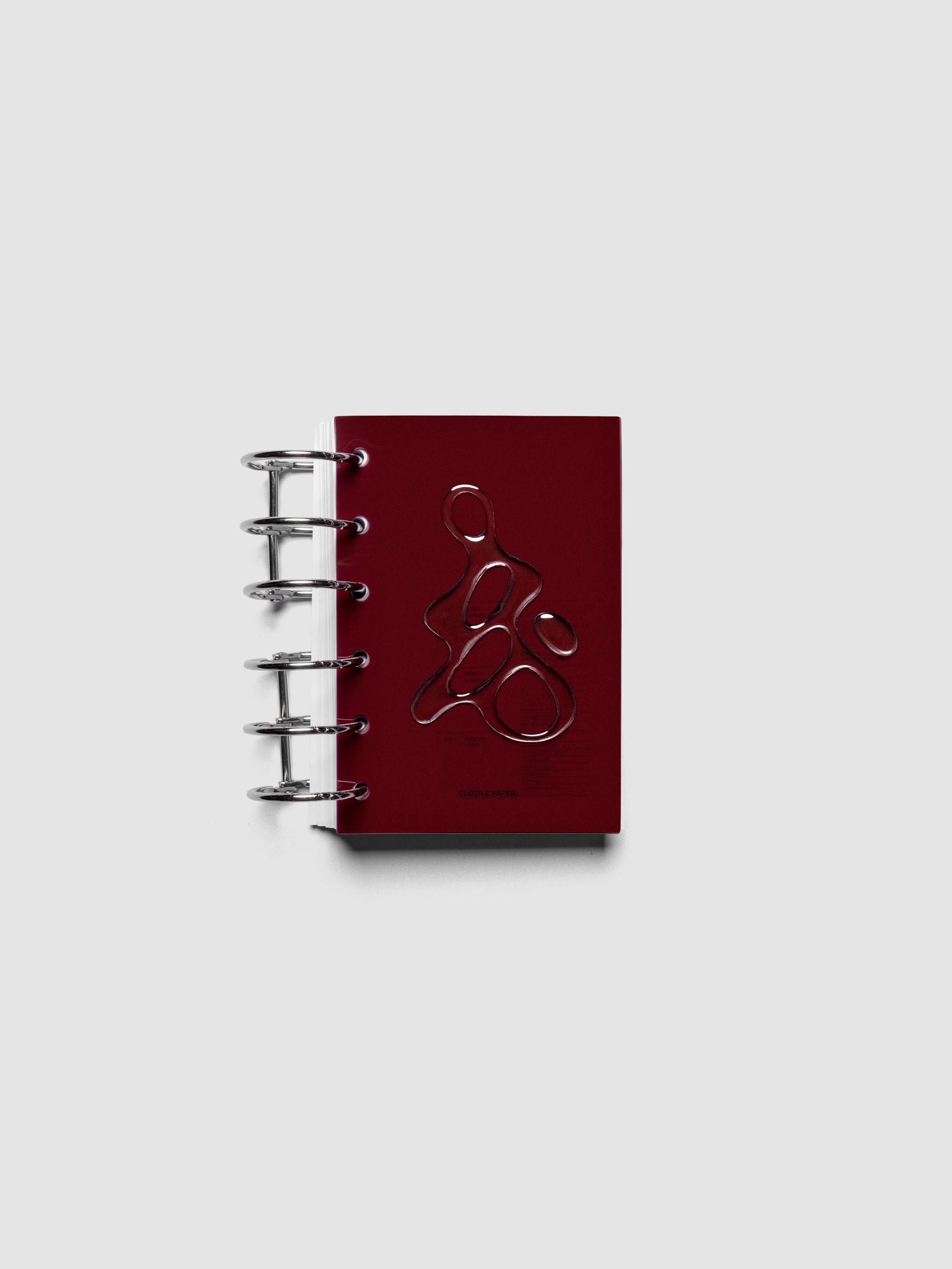 Dark red, semi-transparent, and glossy plastic planner dashboard with organic raised shape design in size Pocket shown ringbound.