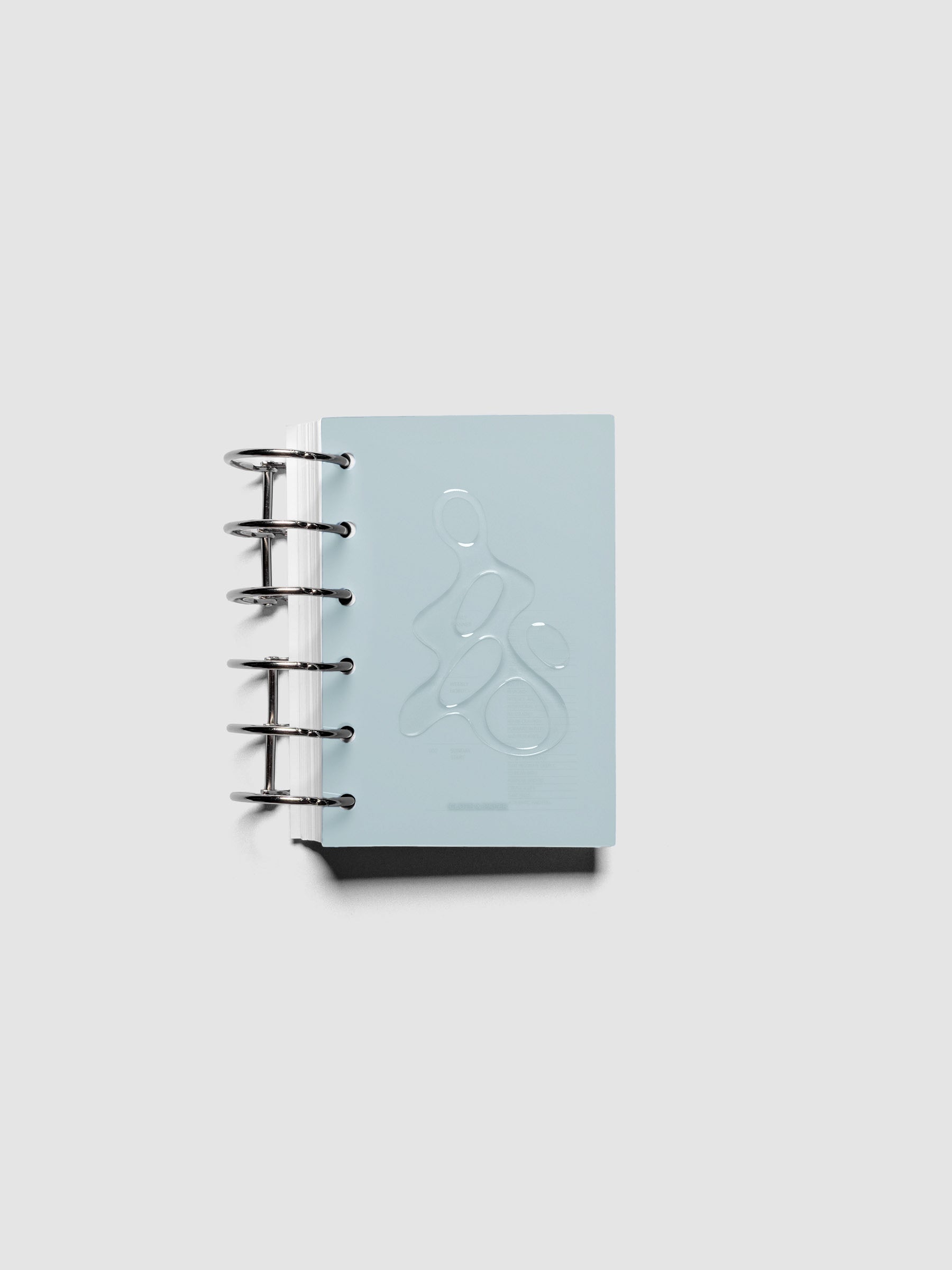 Light blue, semi-transparent, and glossy plastic planner dashboard with organic raised shape design in size Pocket shown ringbound.