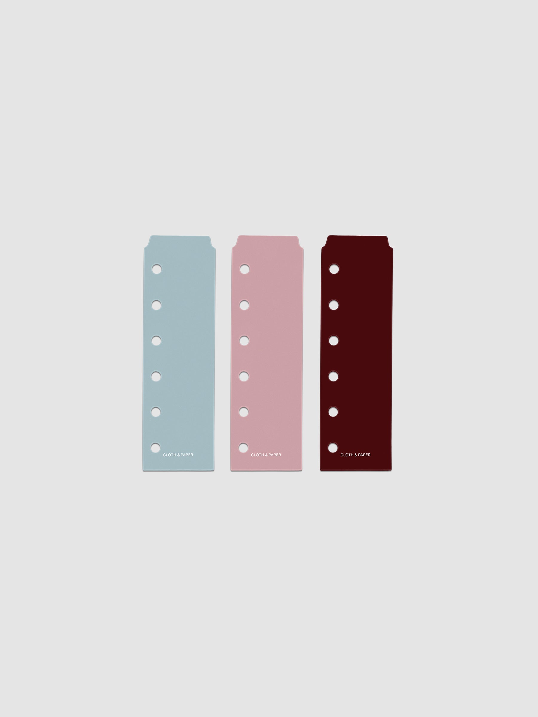 Set of three narrow page markers pre-punched for Pocket planners in light blue, pink, and burgundy on a neutral background.