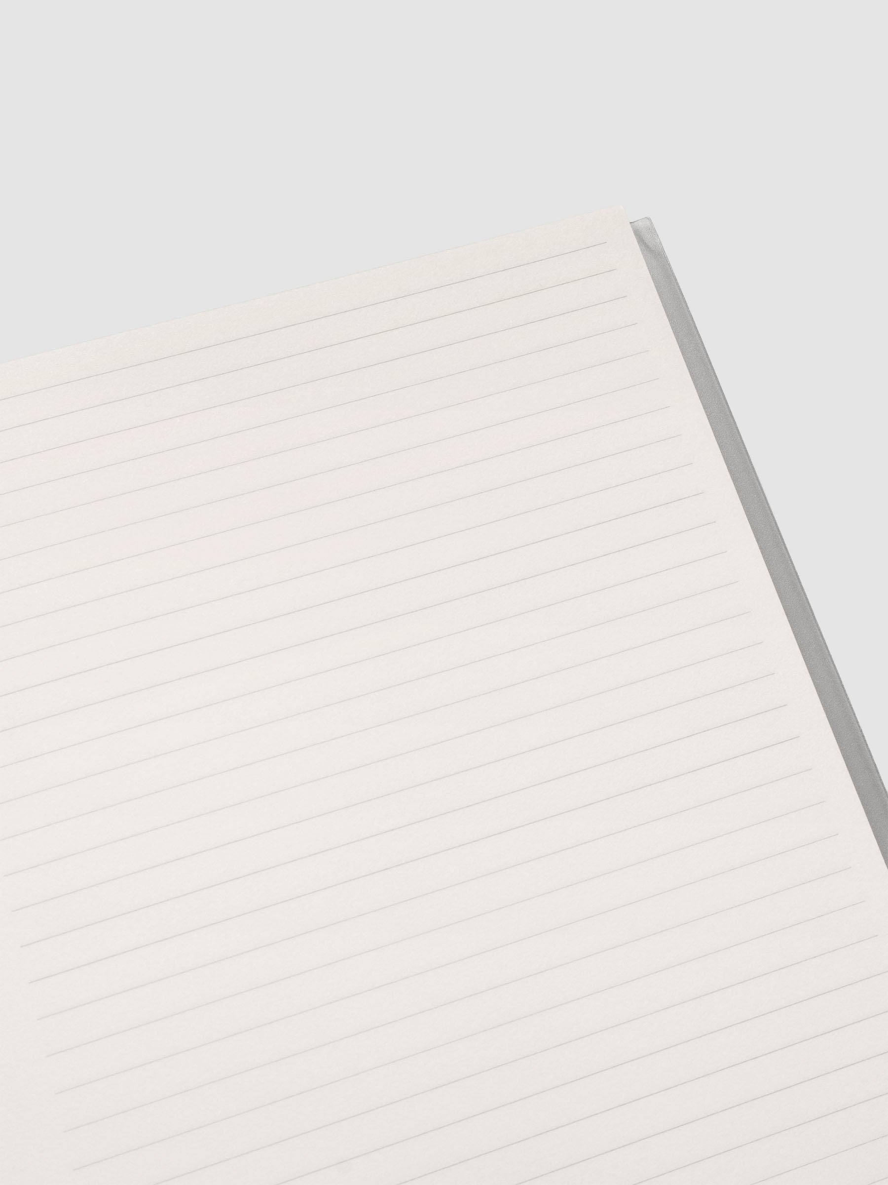 Close up of the Perfect Bound Notebook | A5 | Lined | Ash shown open, laid flat, on a neutral background displaying the lined notes layout.