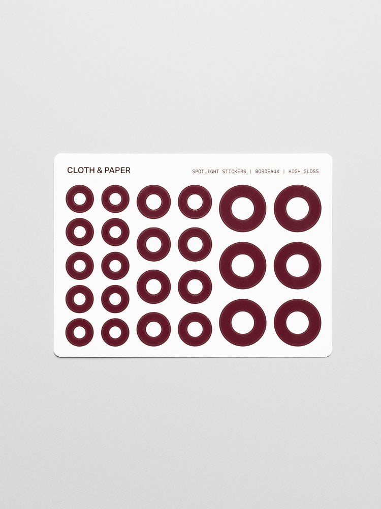 One sticker sheet of burgundy, high-gloss spotlight stickers in small, medium, and large sizes.