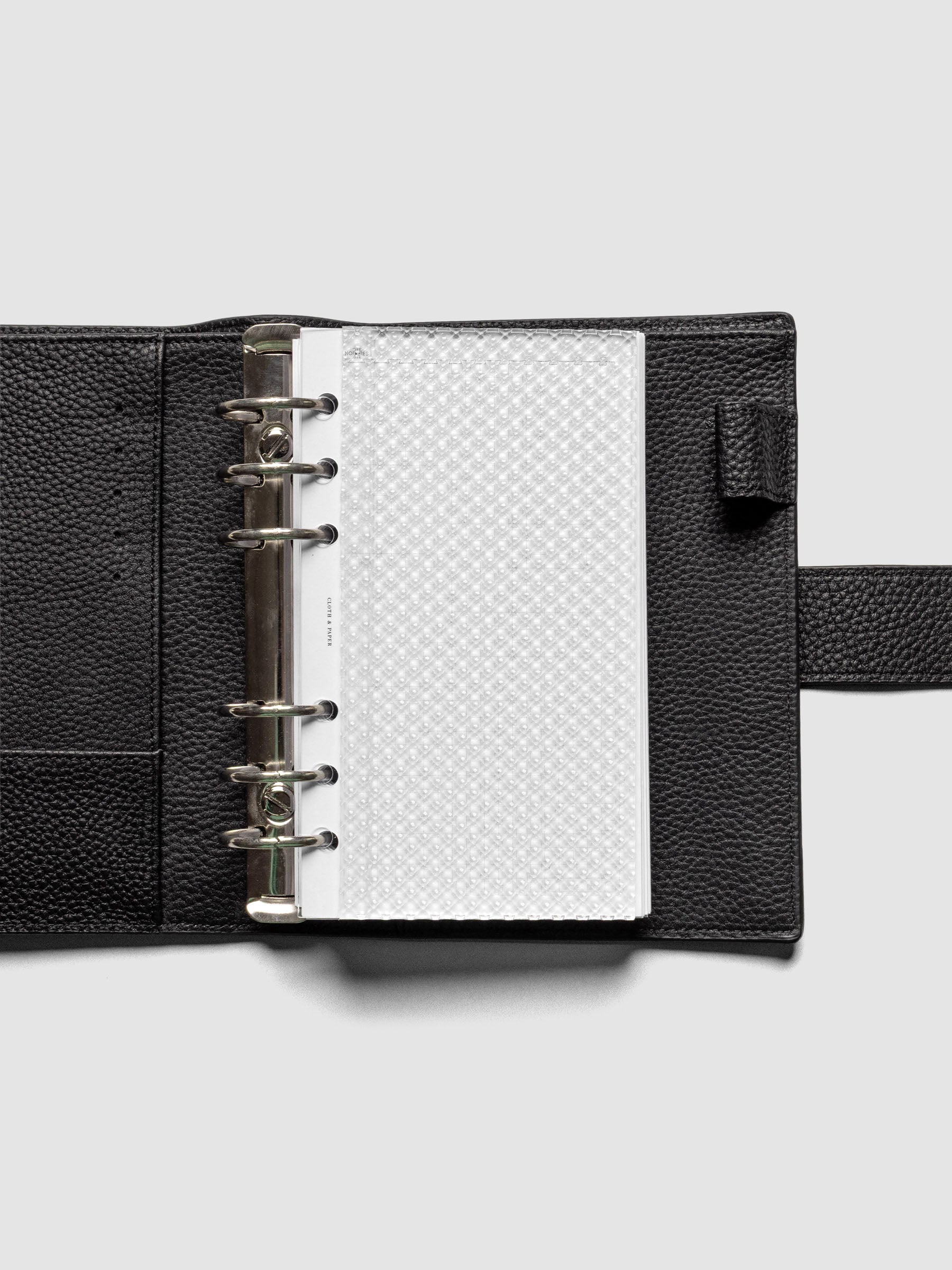 Clear, textured Studded Planner Dashboard in the size Personal, shown ringbound in a black leather agenda.