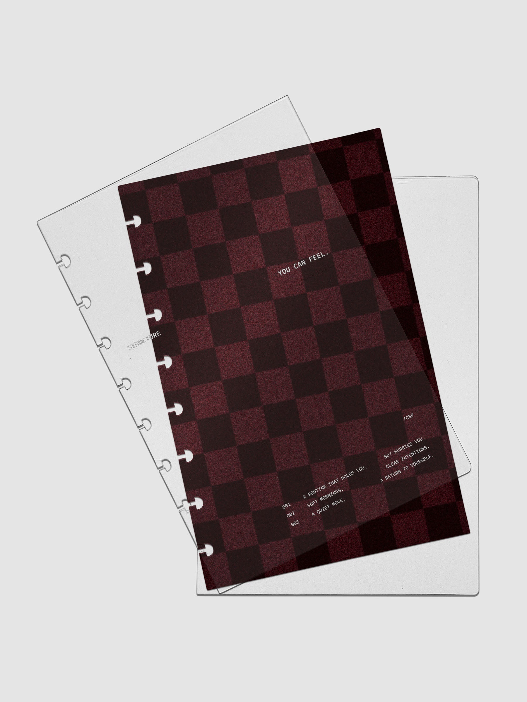 Half Letter sized velvet checkered dashboard in the color Bordeaux in between two crystal clear plastic planner covers with text printed on the cover on the theme of structure and routines.