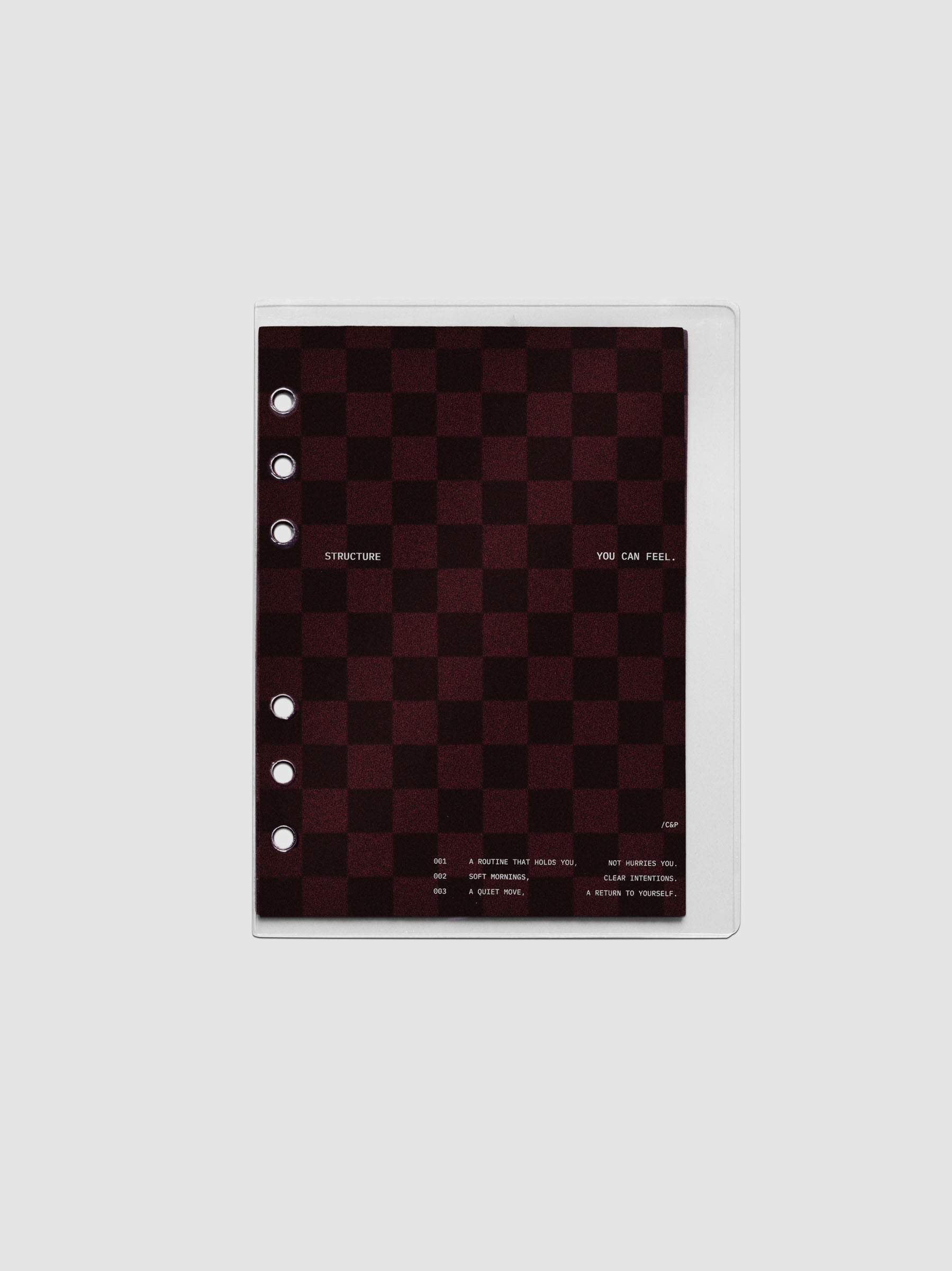 Personal Wide sized velvet checkered dashboard in the color Bordeaux in between two crystal clear plastic planner covers with text printed on the cover on the theme of structure and routines.