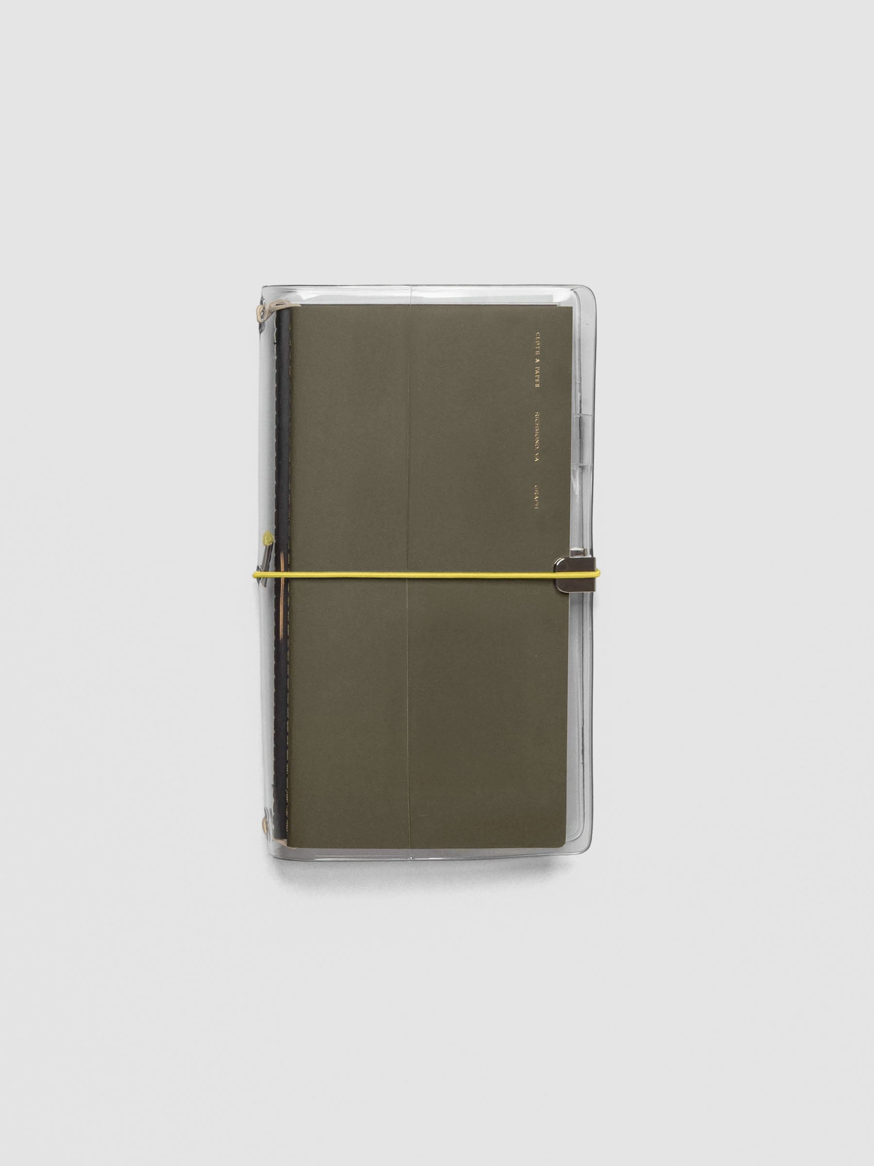 Light yellow exterior band in use with a clear vinyl cover with travel notebooks inside against a neutral background.
