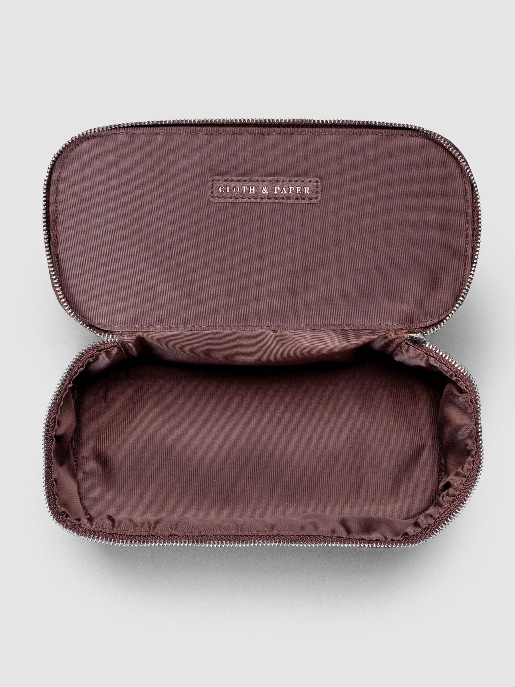 Small packing cube in the color walnut shown unzipped and open against a neutral background.