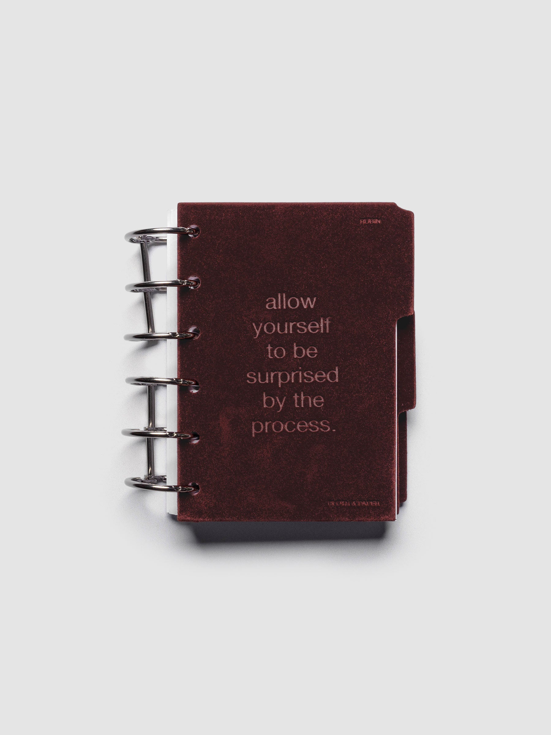 First velvet side tab planners dividers in the color Bordeaux with text deboss design reading "allow yourself to be surprised by the process" in size Pocket shown ringbound.