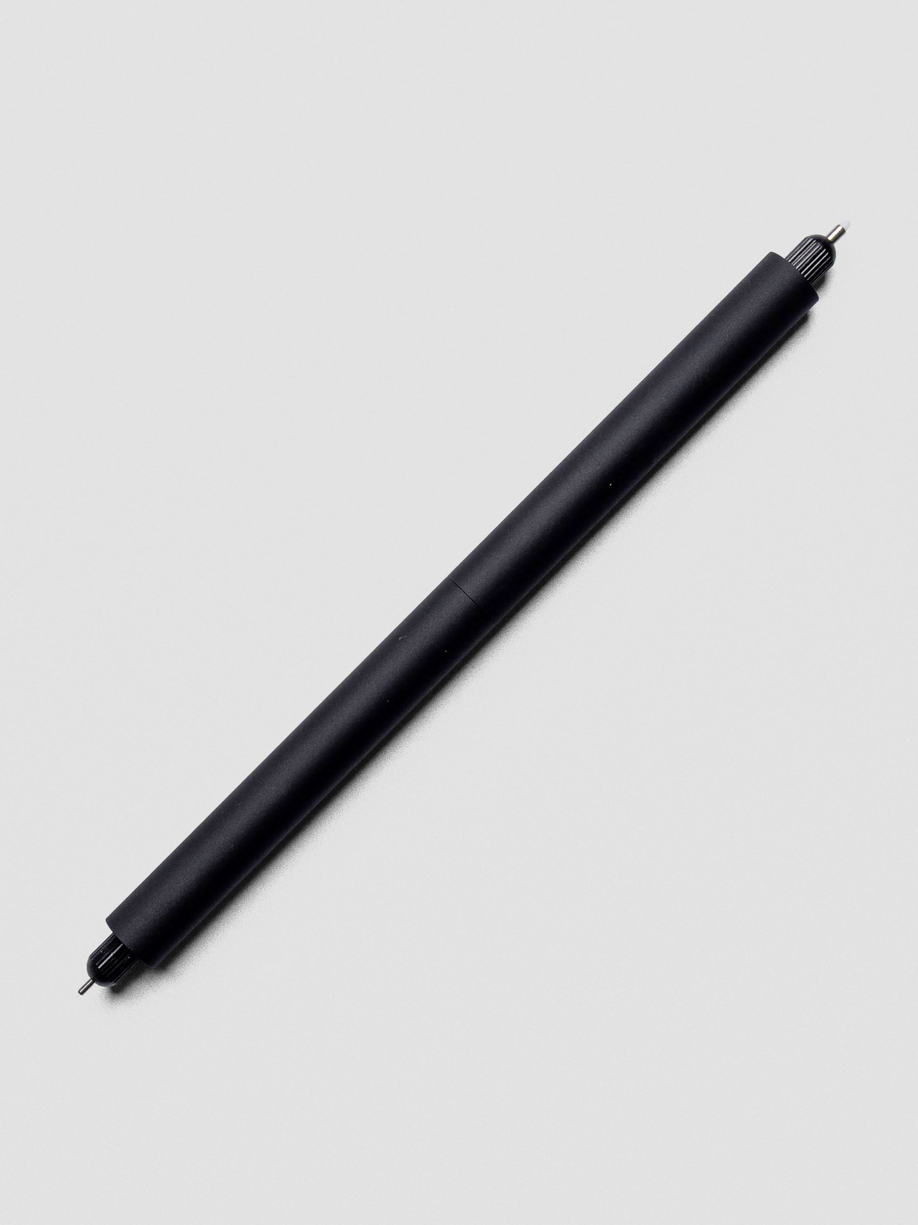 Close-up of Matte Black Lumos Pro Duo Tip Pen angled across a notebook page, uncapped on both ends.