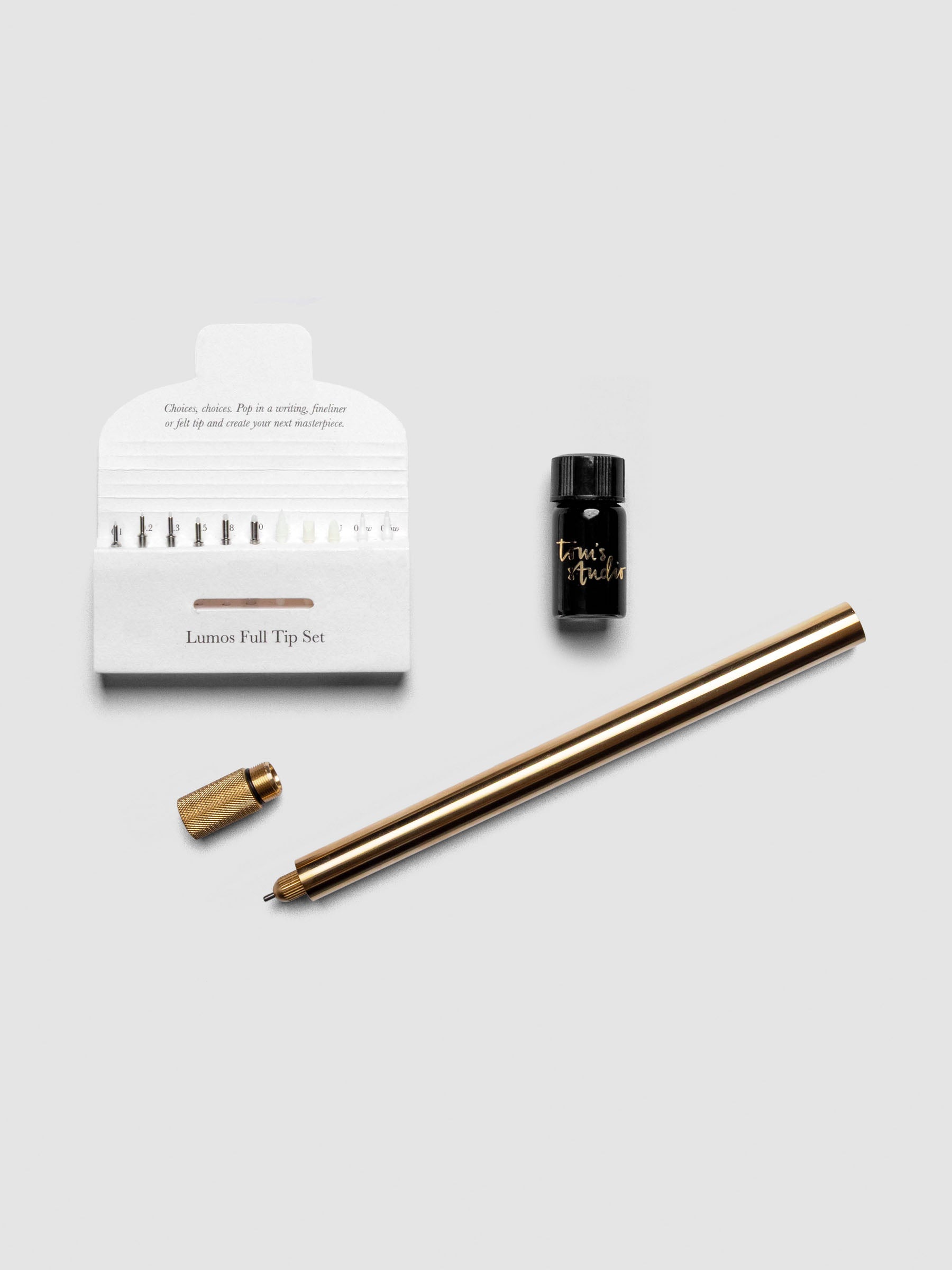 Brass Lumos Pro Single Tip Pen diagonally, uncapped, with nib set and ink resevoir.