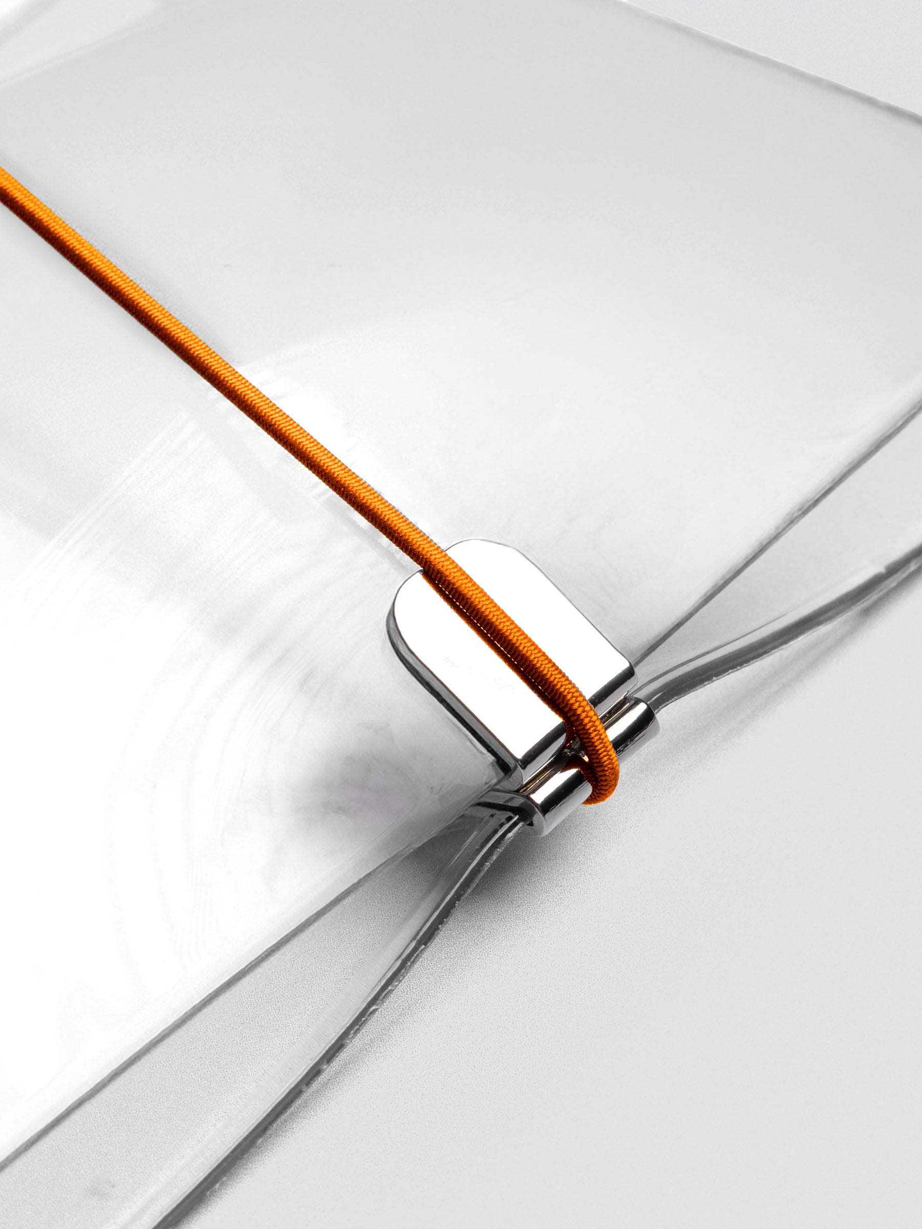 Orange elastic band stretched across clear vinyl cover, anchored at metal clasp.
