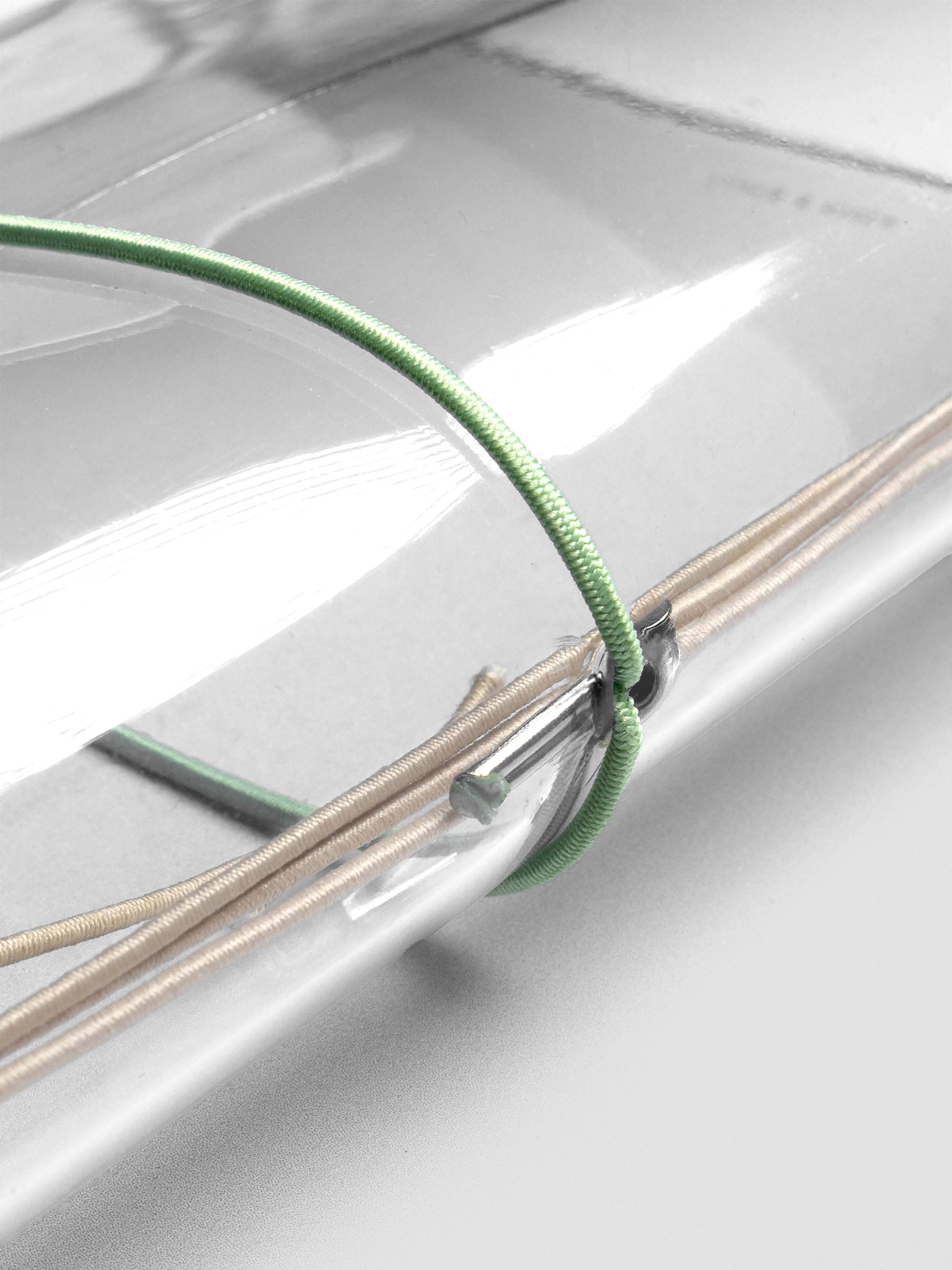 Sage green elastic exterior band looped through clear vinyl cover spine.