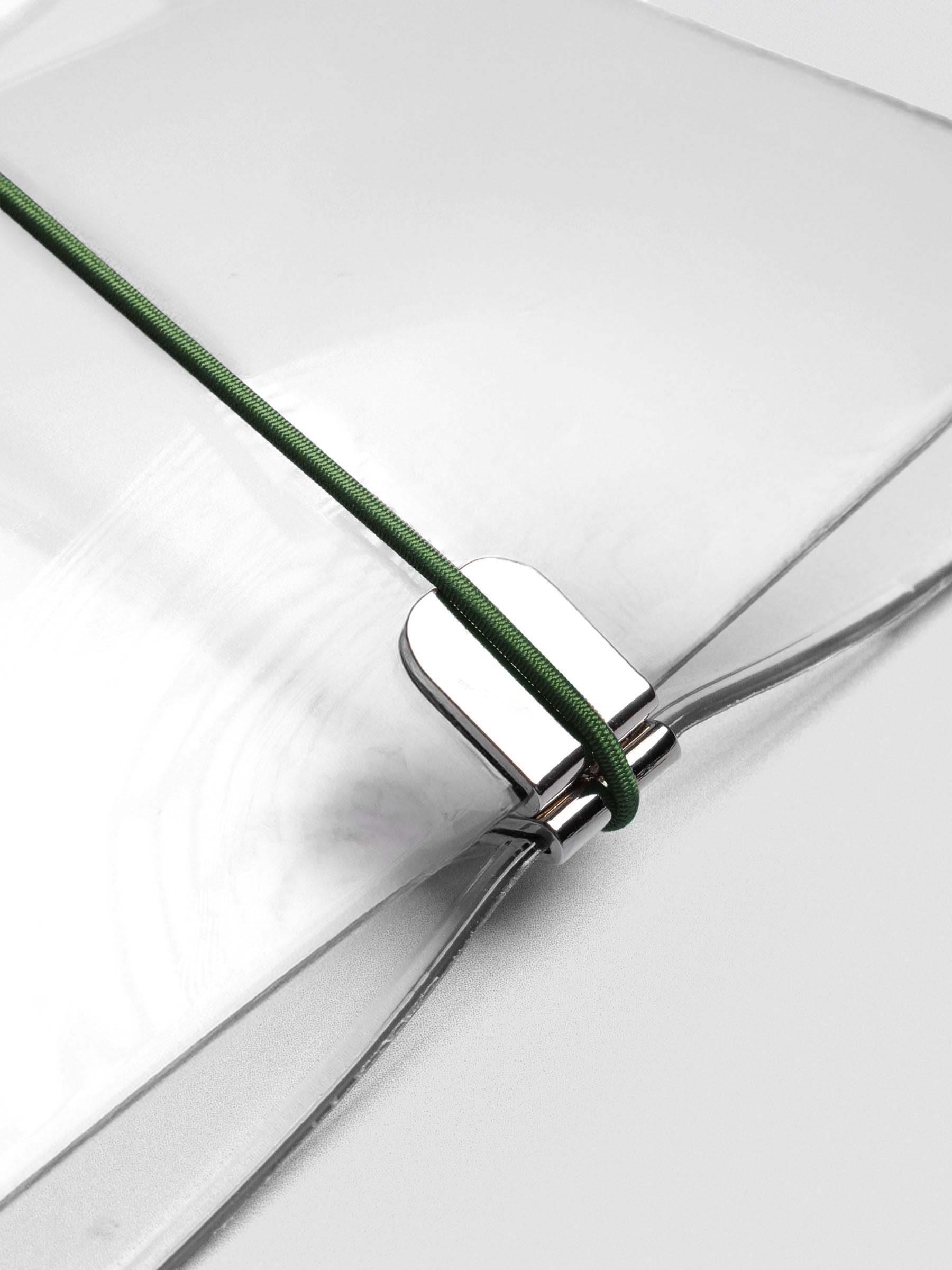 Dark green elastic band stretched across clear vinyl cover, anchored at metal clasp.