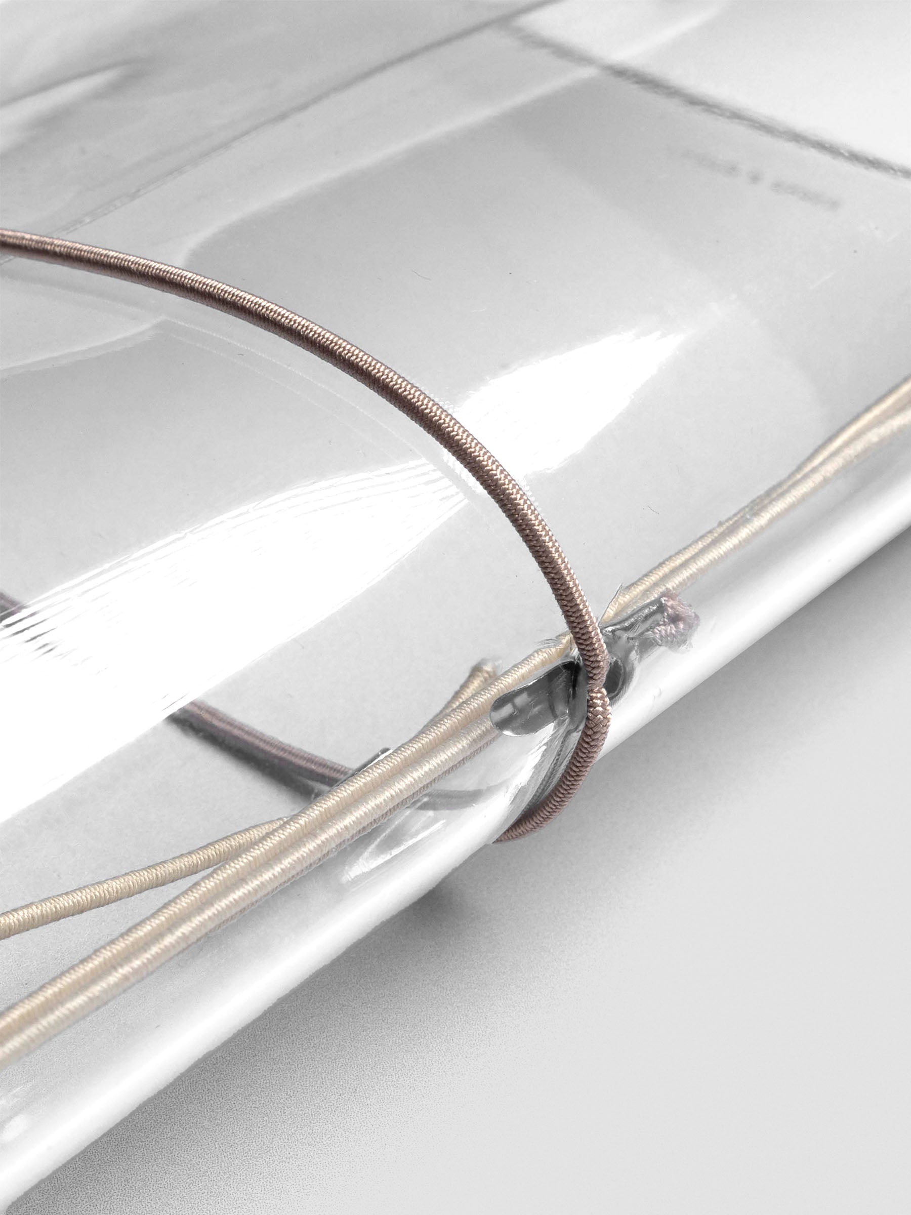 Taupe elastic exterior band looped through clear vinyl cover spine.
