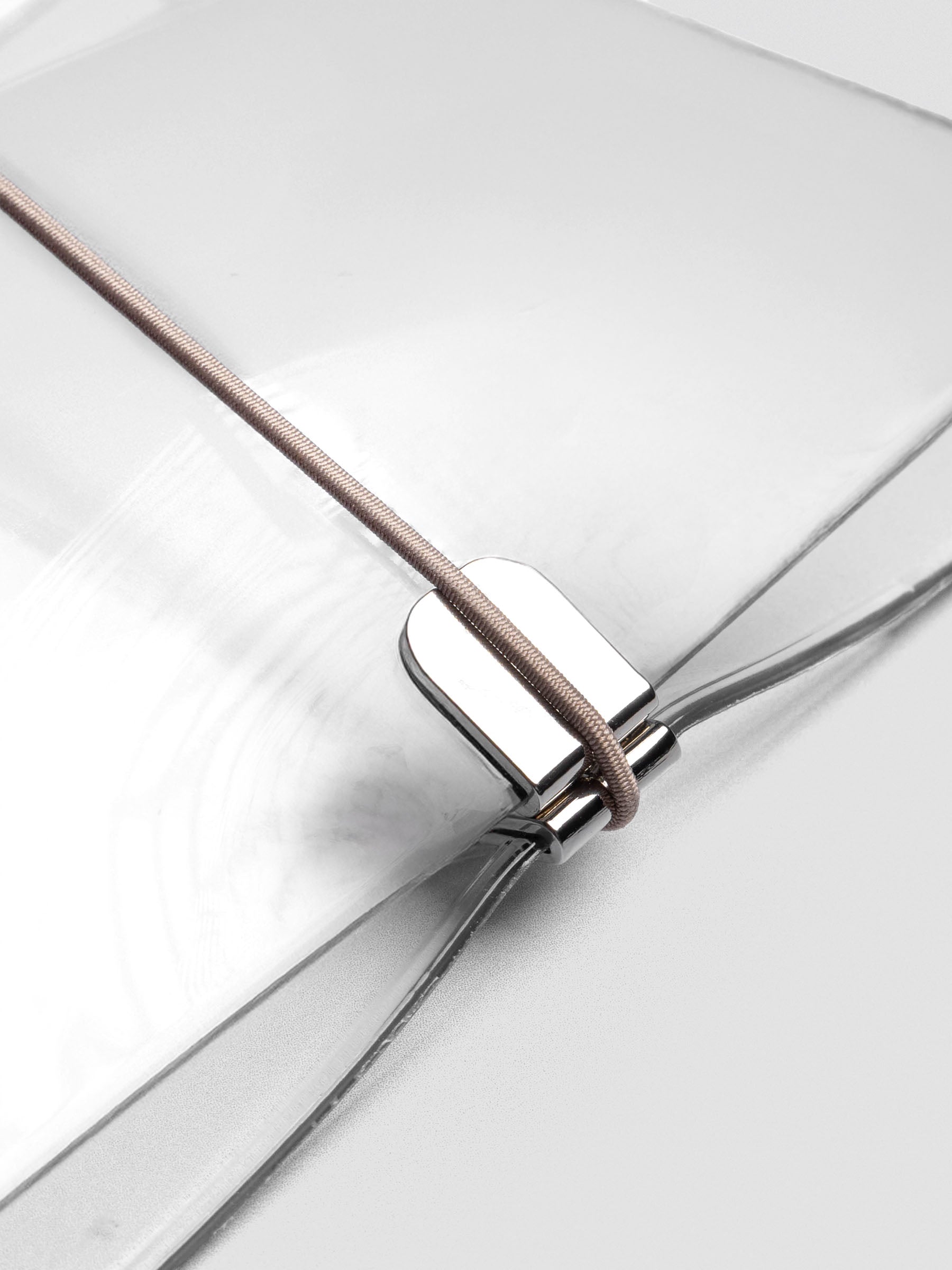 Taupe elastic band stretched across clear vinyl cover, anchored at metal clasp.