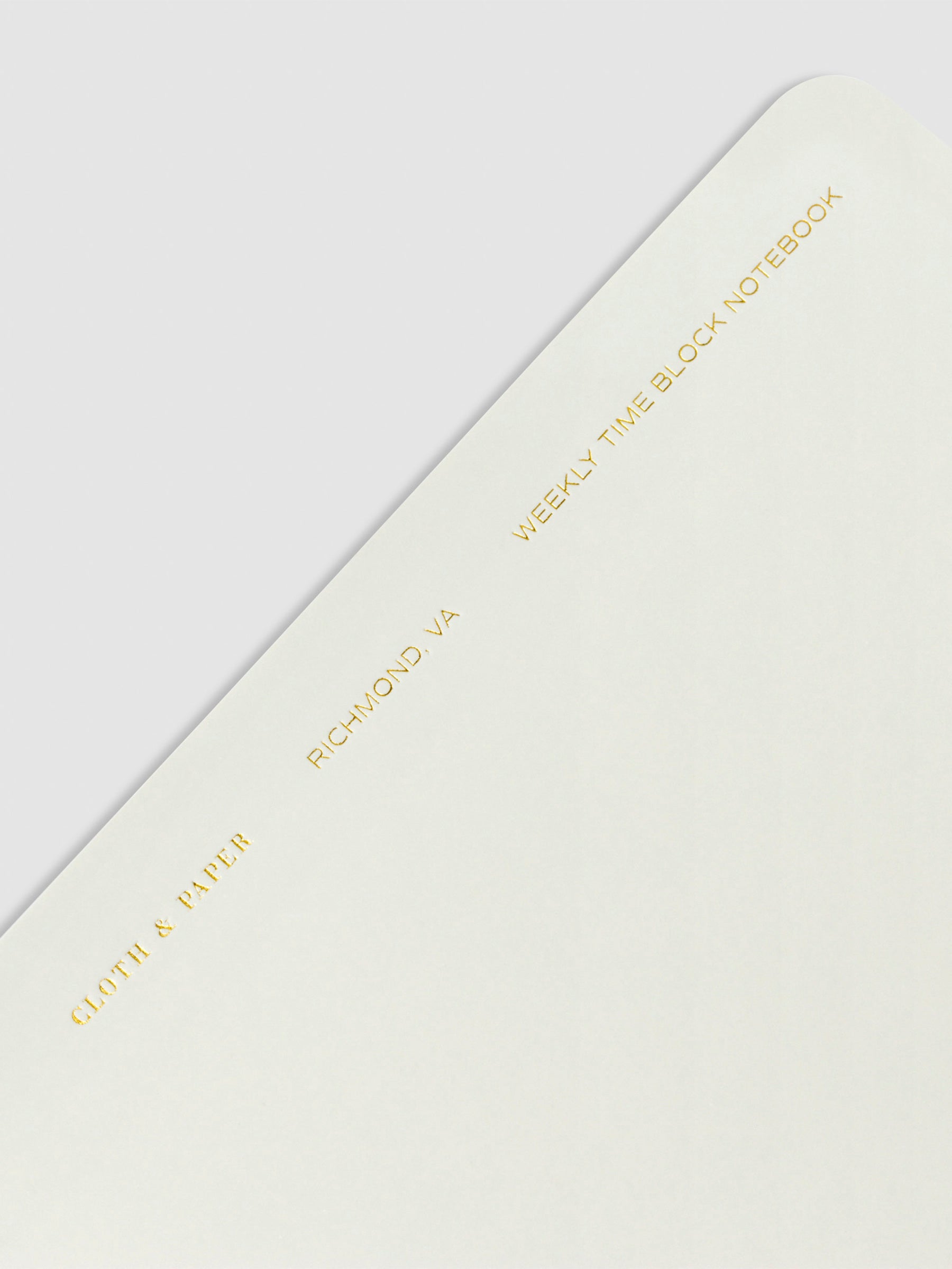 Closeup of text at the top of the notebook. Text reads "Cloth and Paper, Richmond, VA, Weekly Time Block Notebook" in gold foil print.