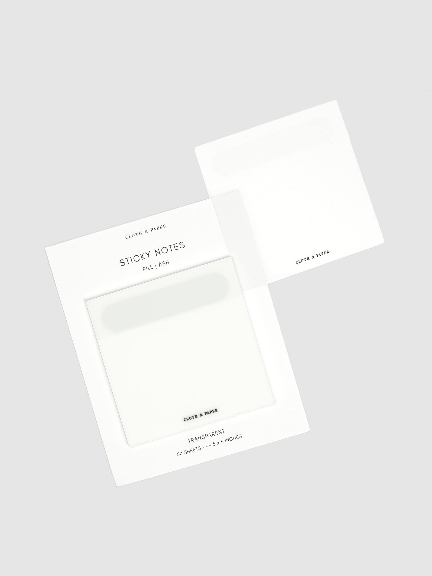 Ash sticky notes on their backing displayed on a neutral background. One note is removed and placed on the edge of the backing to display its transparency.