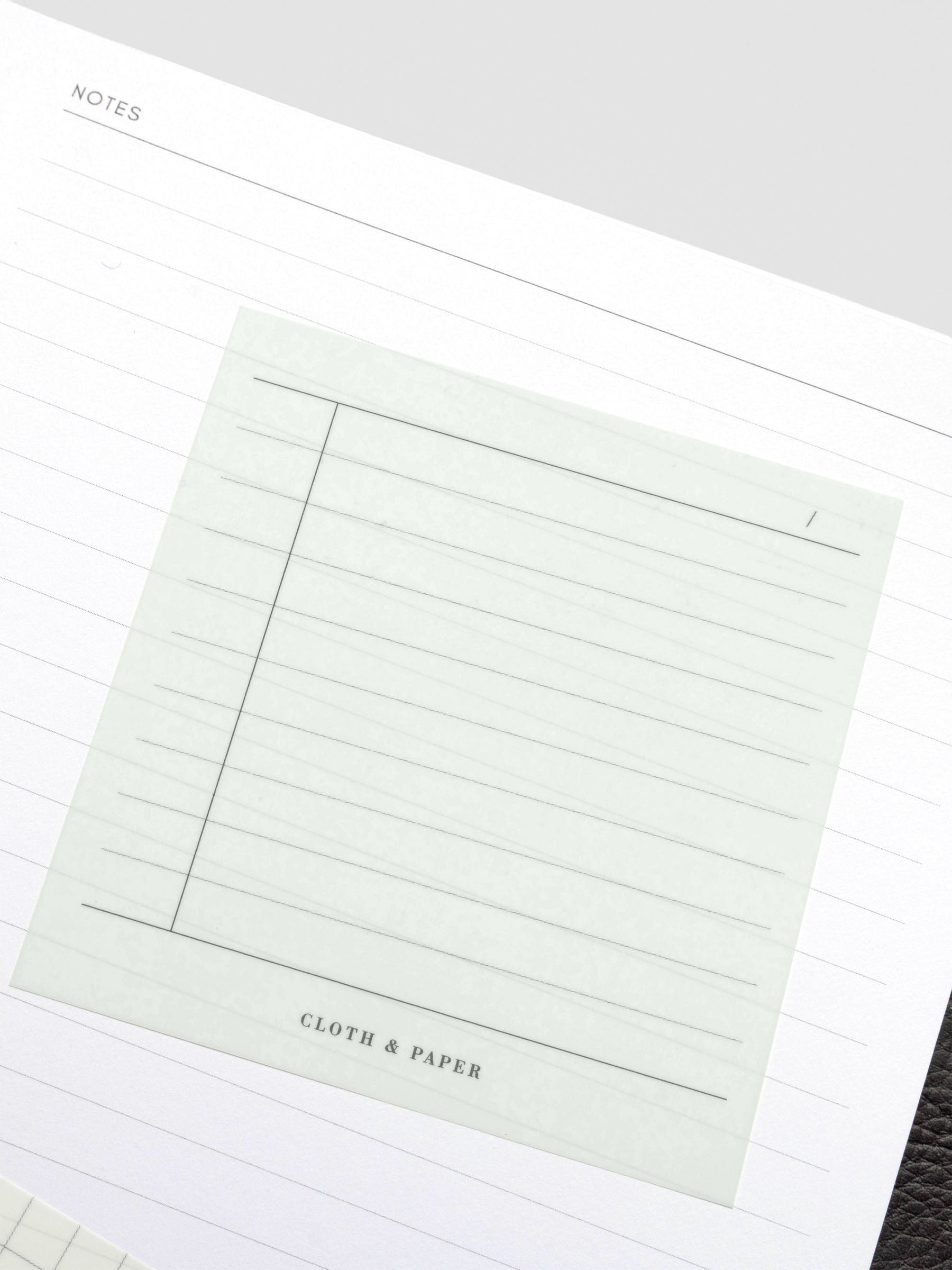 Transparent sticky note placed on a planner page, showing its see-through design over lined paper.