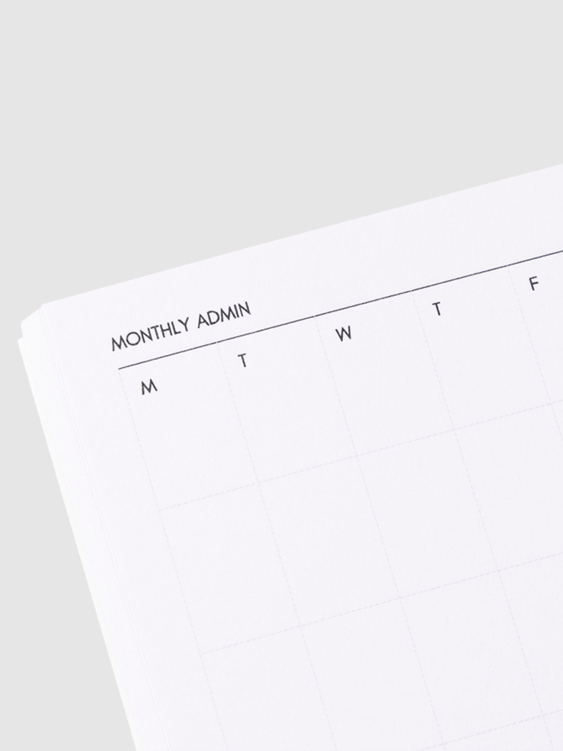 Close up image of the top left corner of the monthly notebook page. The page is turned on a left angle and is displayed on a light gray background