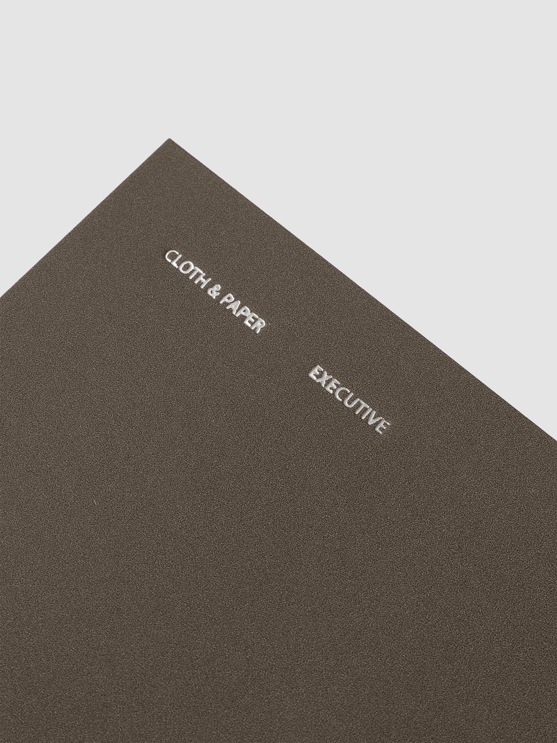 Close up of cover foil details on the Travel Notebook | Pocket Plus | Cafe Noir | Executive shown against a neutral background.