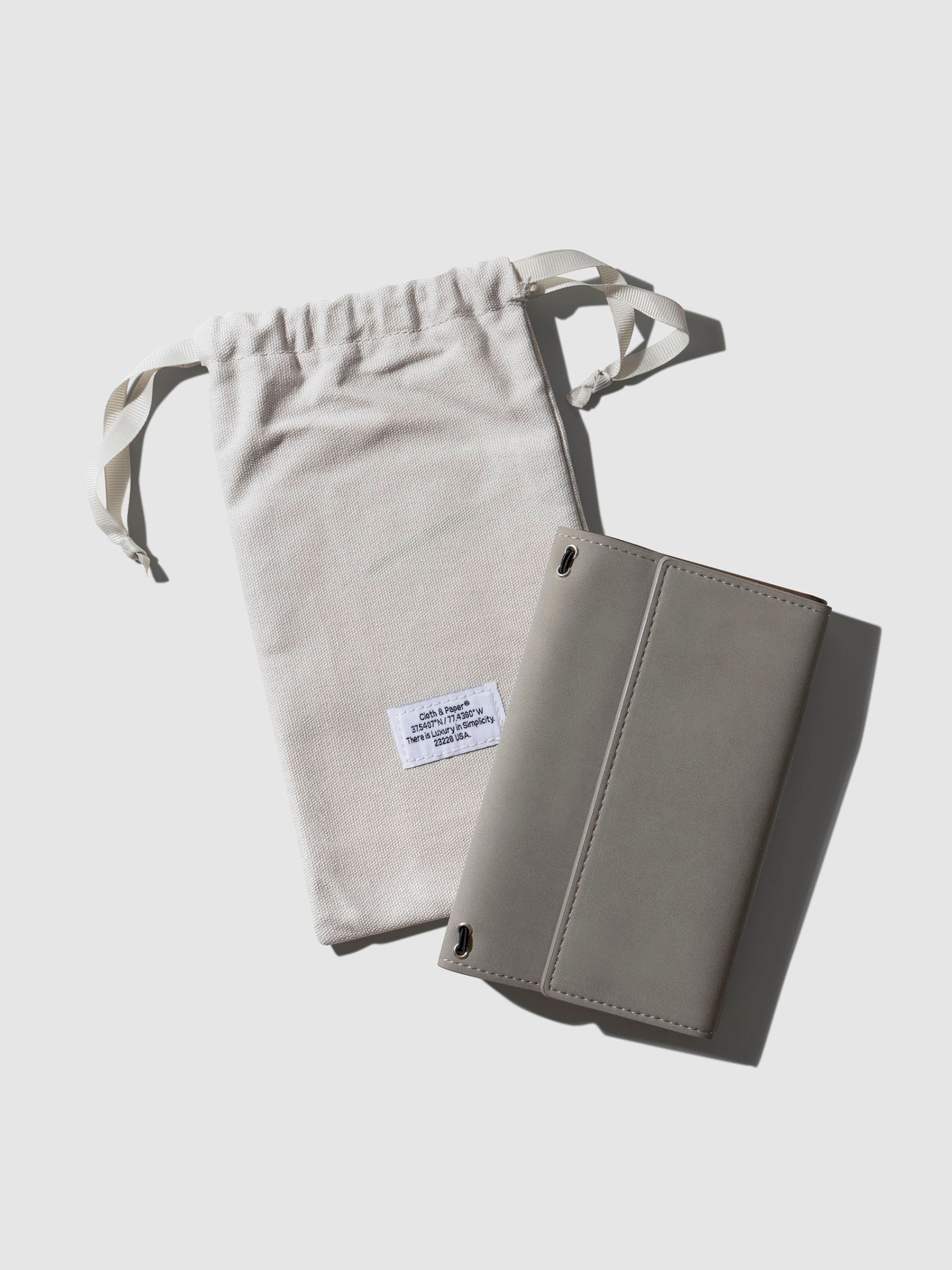 Travel Refillable Notebook Cover, Ristretto, Cloth and Paper. Notebook cover shown with dust bag on a neutral background.