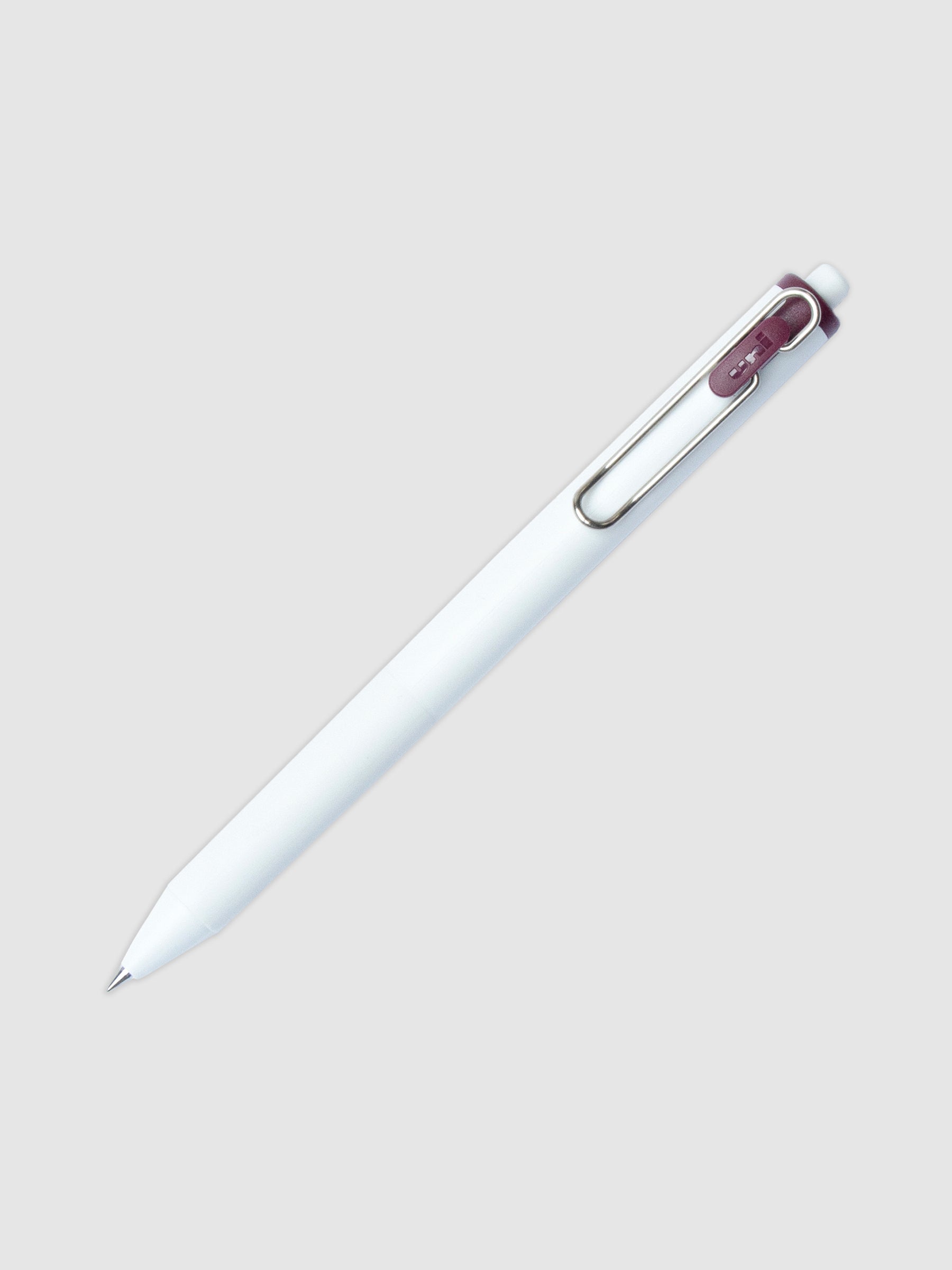 Uni-ball One Gel Pen, Bordeaux Black, Cloth and Paper. Pen tilted slightly to the right on a neutral background.