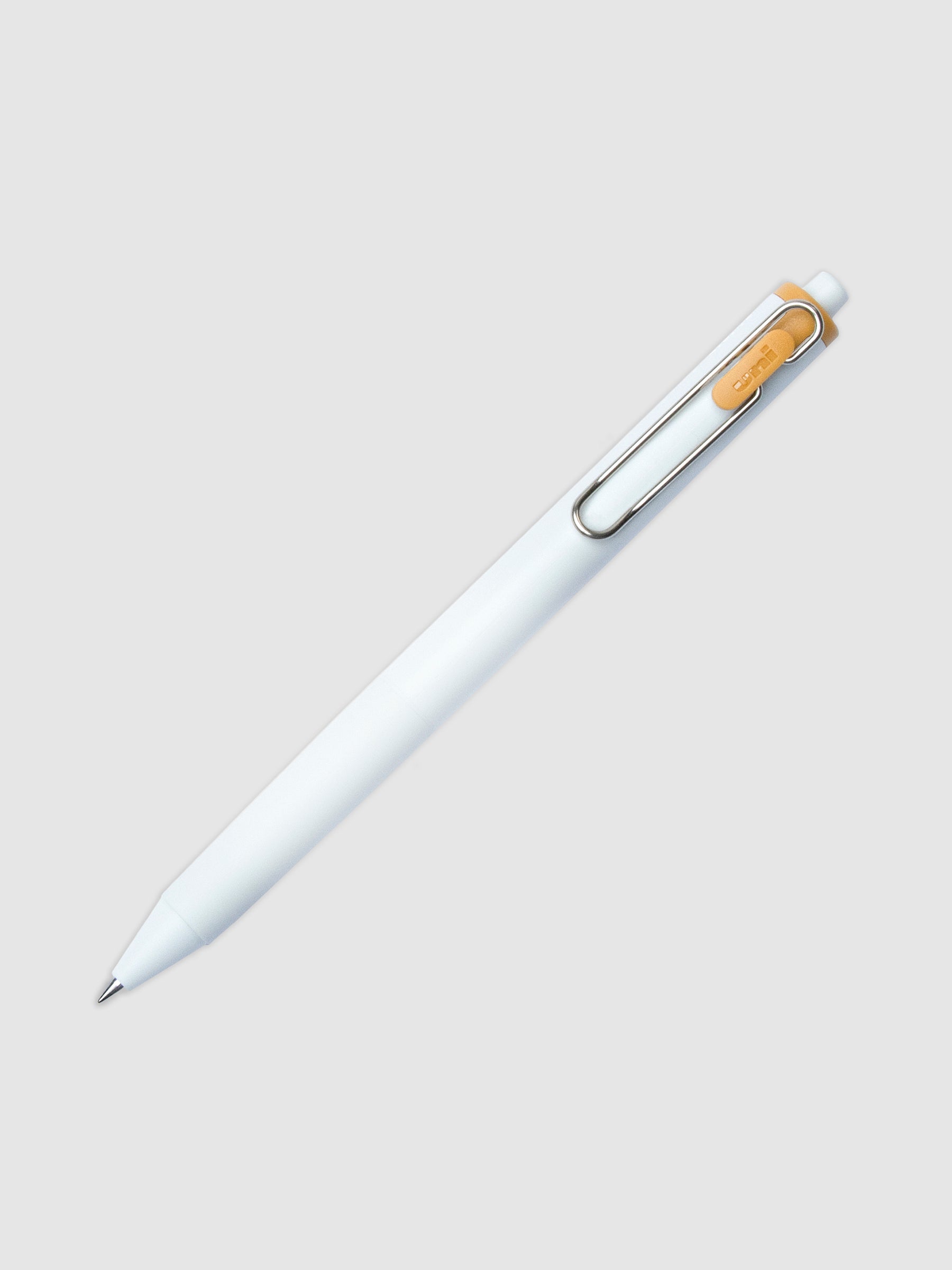 Uni-ball One Gel Pen, Caramel, Cloth and Paper. Pen tilted slightly to the right on a neutral background.