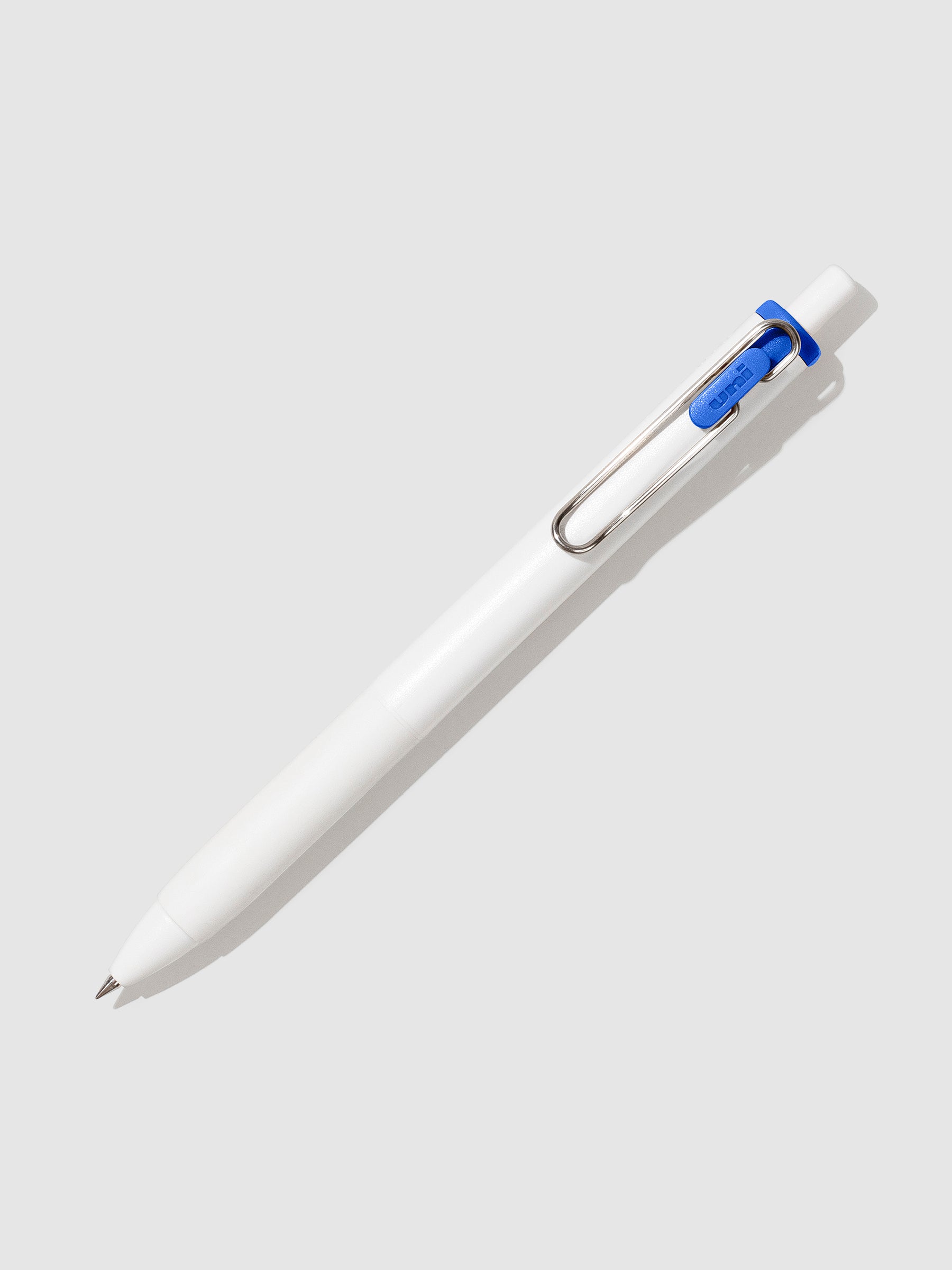 Uni-ball One Gel Pen, Blue, Cloth and Paper. Pen tilted slightly to the right on a neutral background.