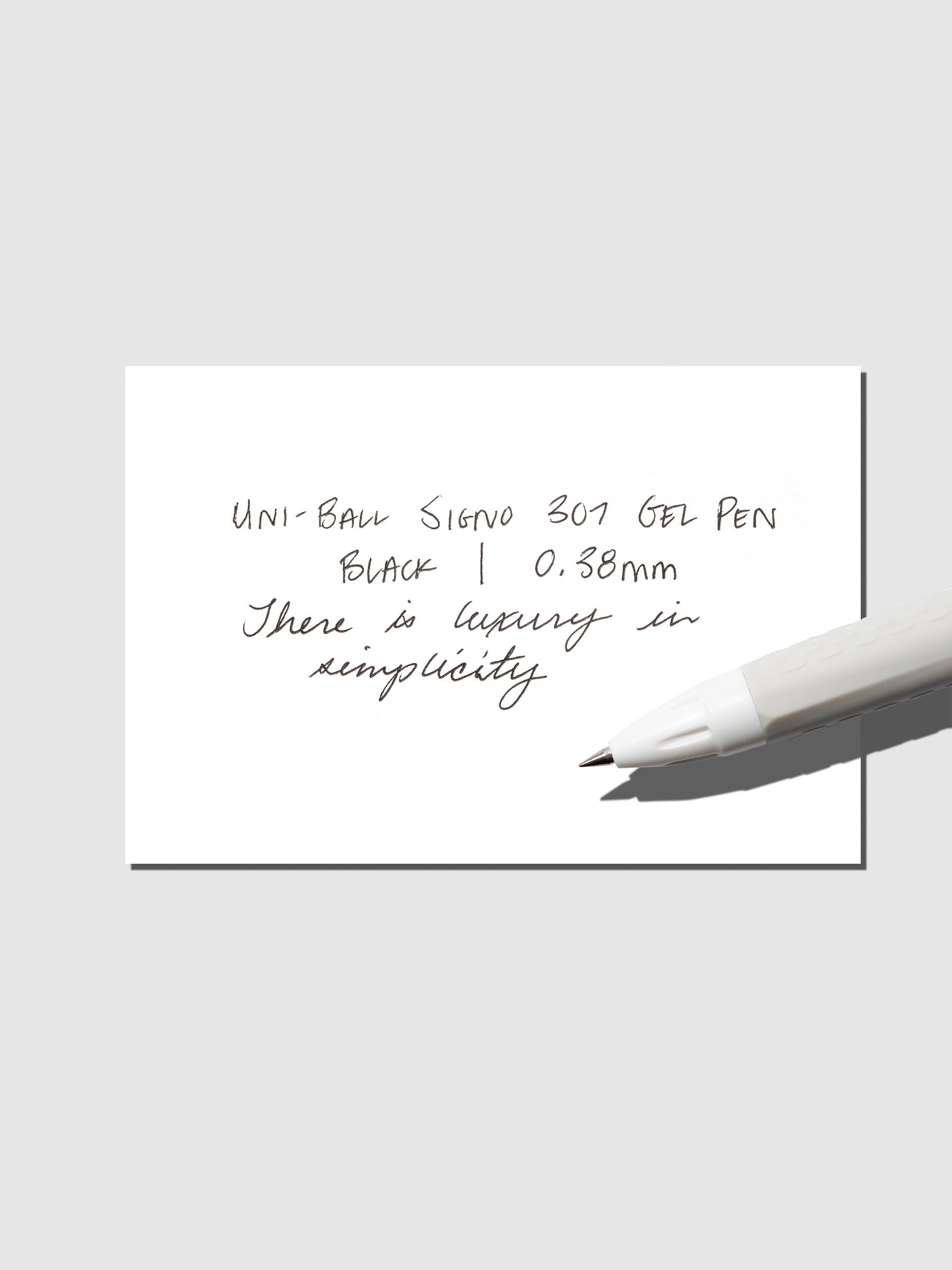 Uni-Ball Signo Gel pen resting on a pen test sheet. The sheet shows the pens specs. Color pictured is Black.