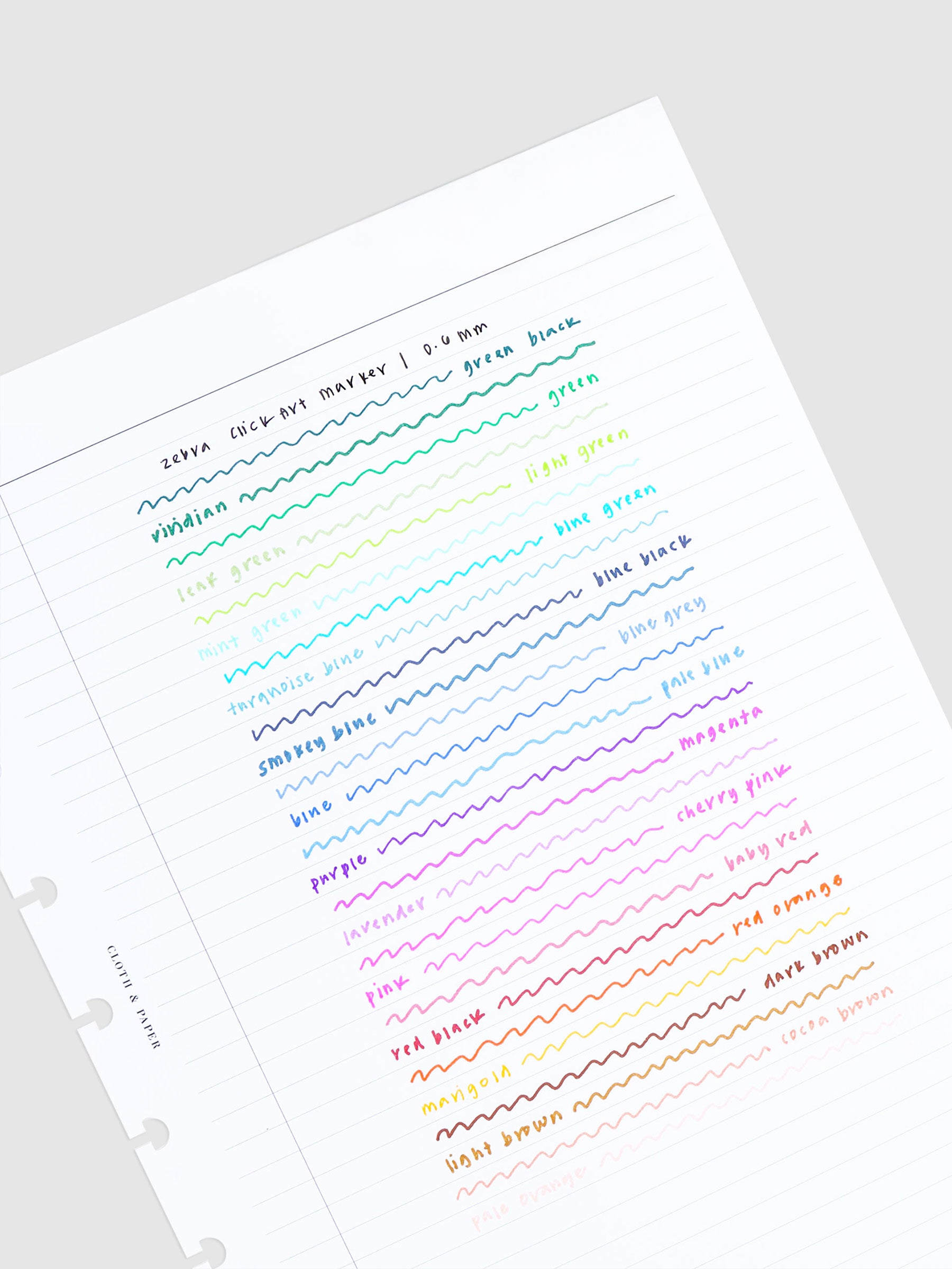 Test writing of all Zebra ClickArt Marker colors on a lined paper, on a neutral background, tilted slightly to the left.