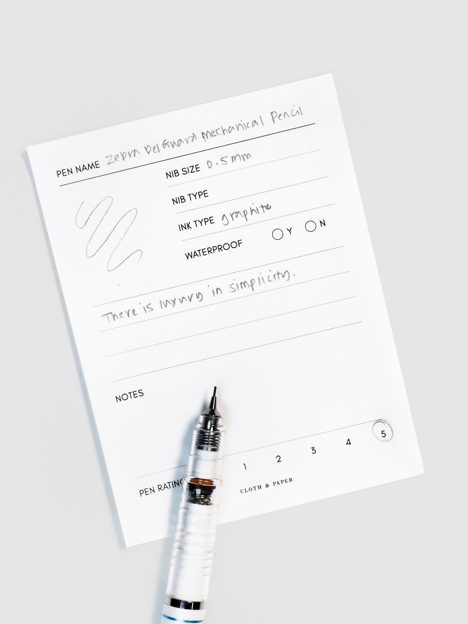 Pencil resting on a pen test sheet displaying a writing sample detailing the pencil's specs.
