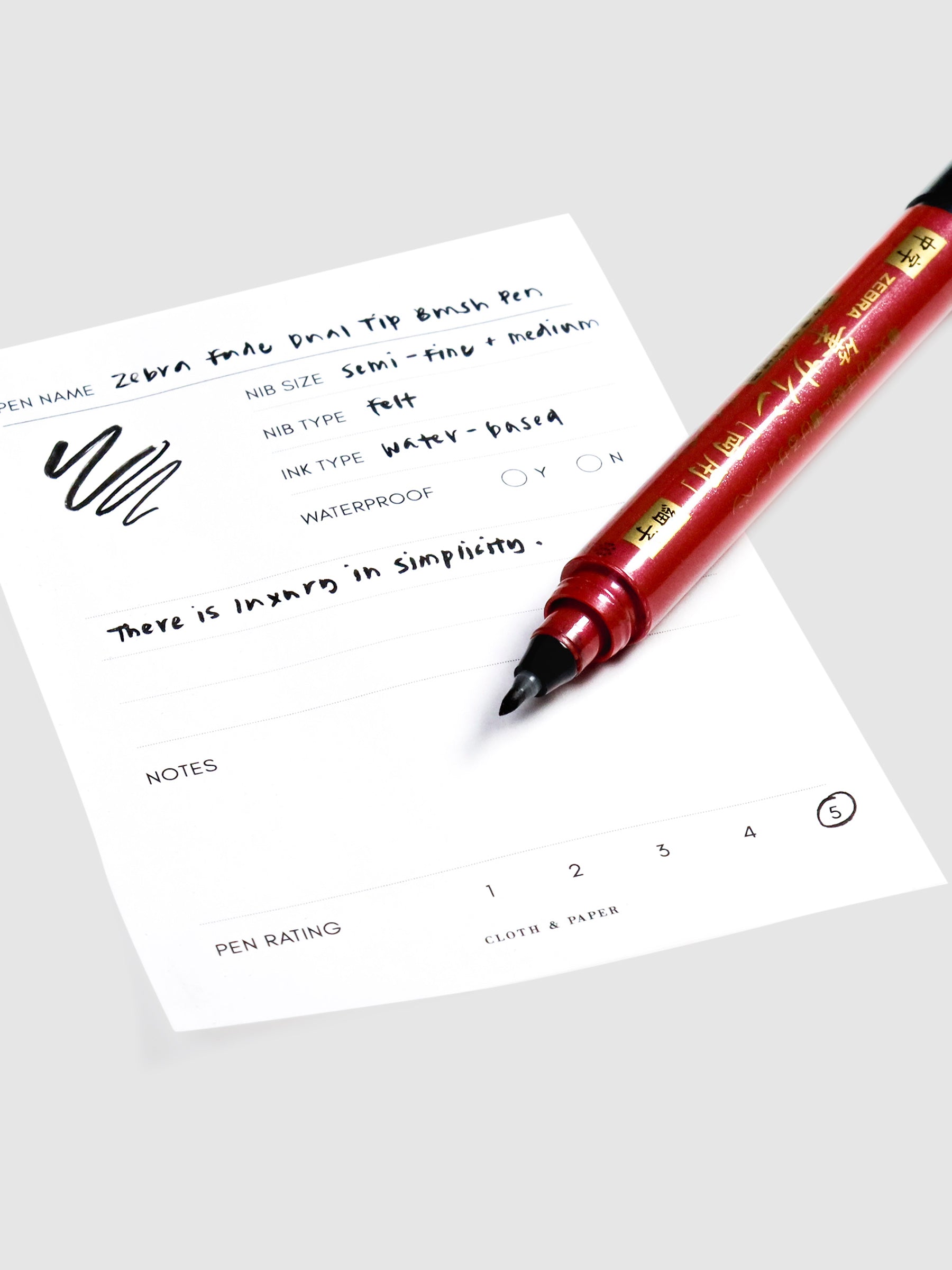 Close up on fine tip nib of brush pen resting on pen test sheet.