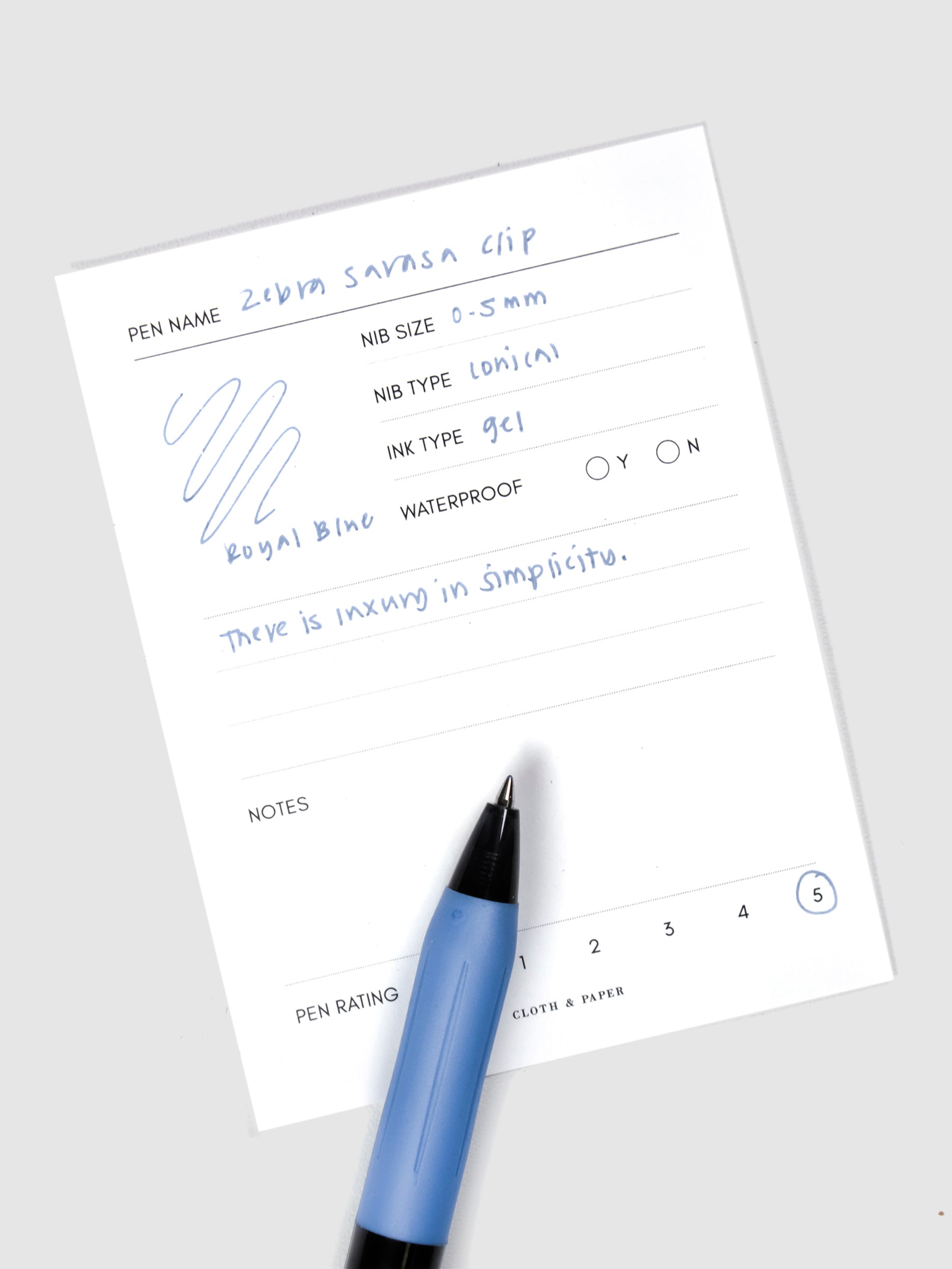 Pen resting on a pen test sheet displaying a writing sample detailing the pen's specs.