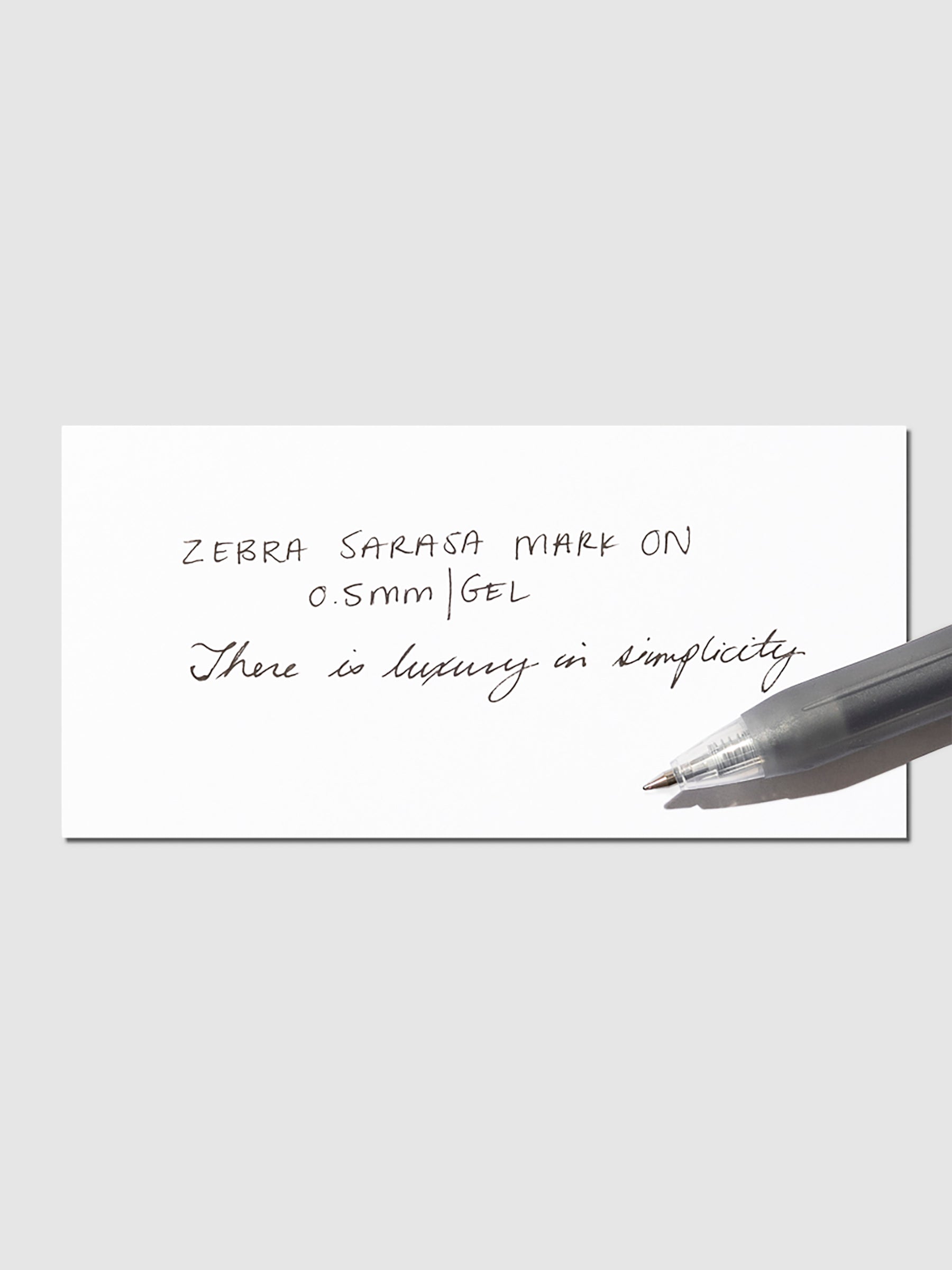 Pen in Black resting on a pen test sheet displaying a writing sample detailing the pen's specs.