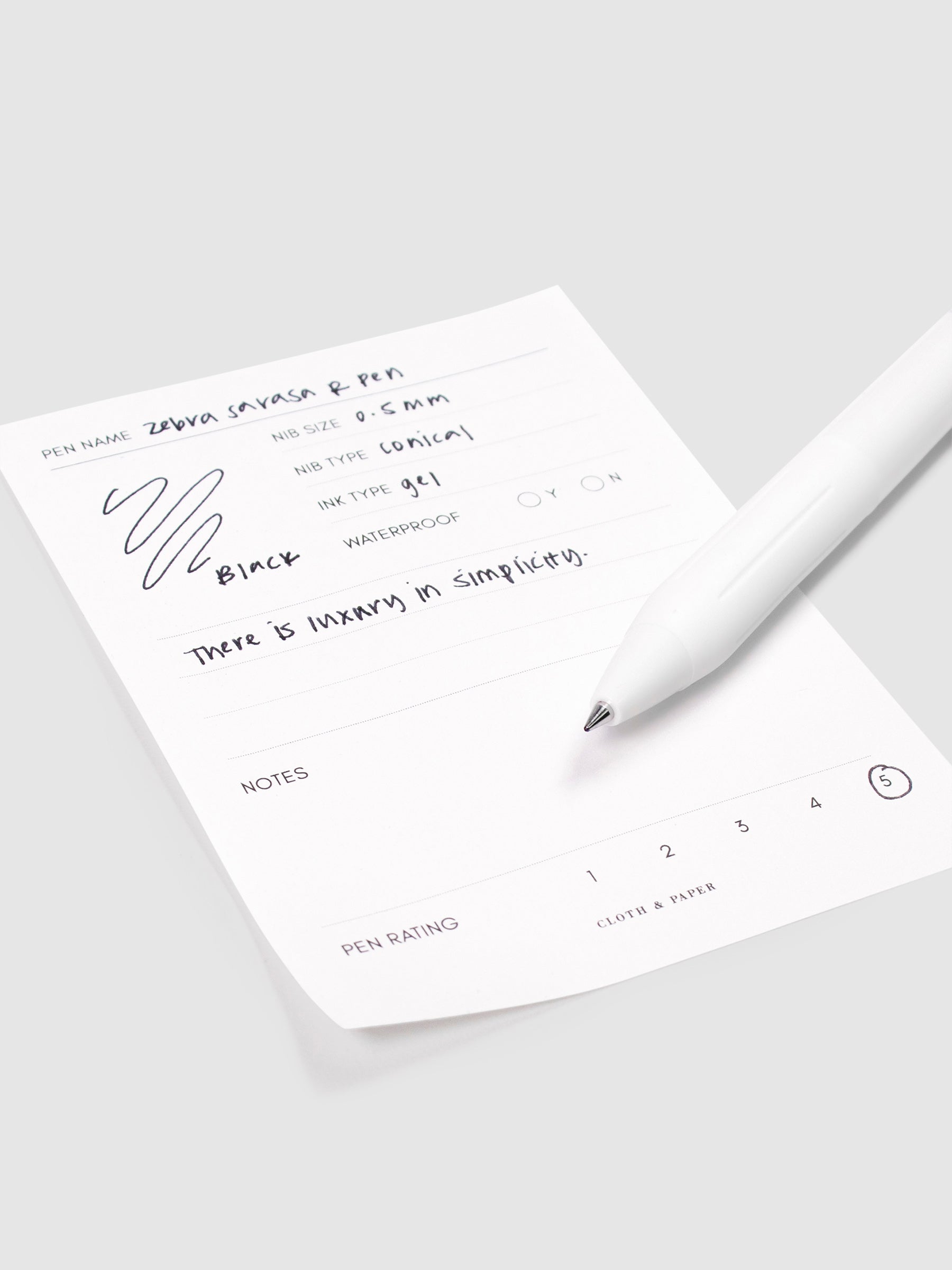 Zebra Sarasa R Pen, 0.5 mm, Black, Cloth and Paper. Close up on pen nib resting on pen test sheet.