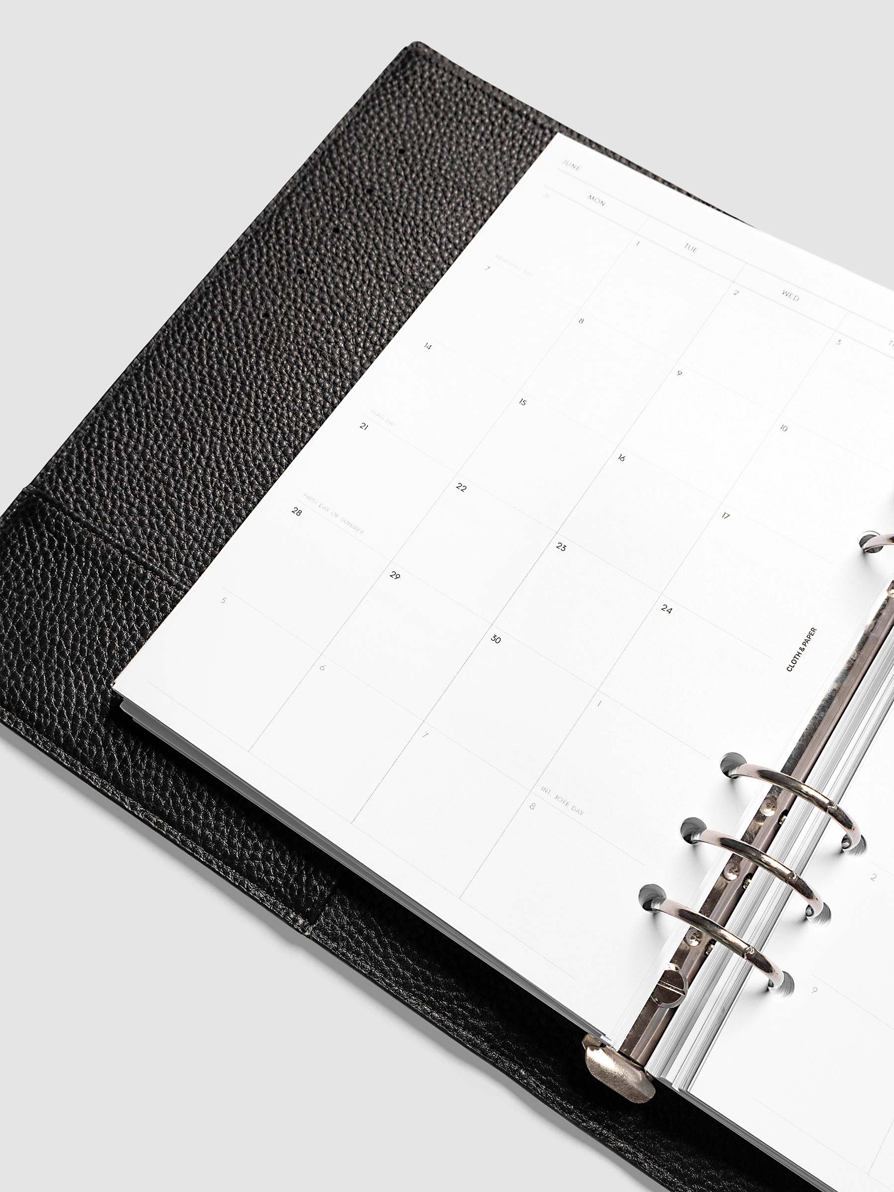 2027 Dated Monthly Planner Inserts, Monday Start, A5 6-Ring Punch, close-up detail of left page showing holidays and observances labeled on monthly calendar shown inside a planner