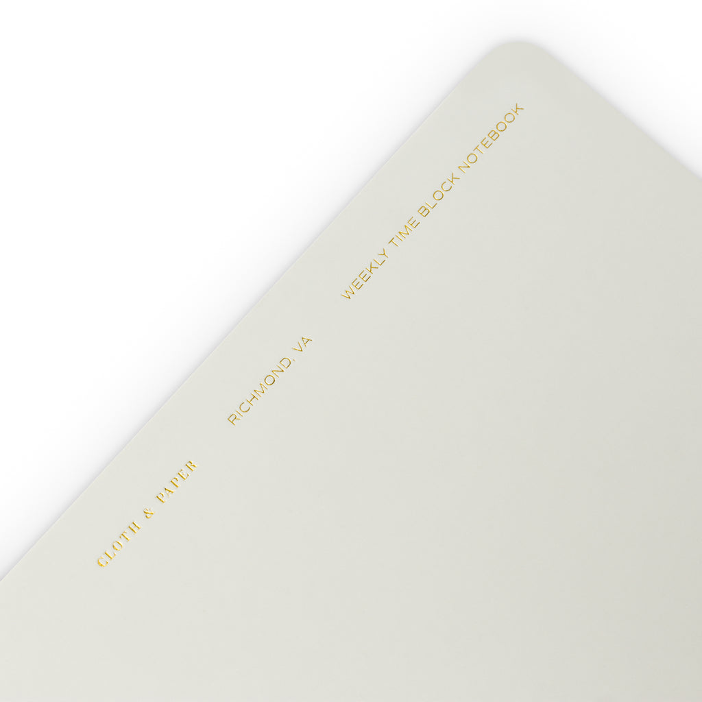 Closeup of text at the top of the notebook. Text reads "Cloth and Paper, Richmond, VA, Weekly Time Block Notebook" in gold foil print.